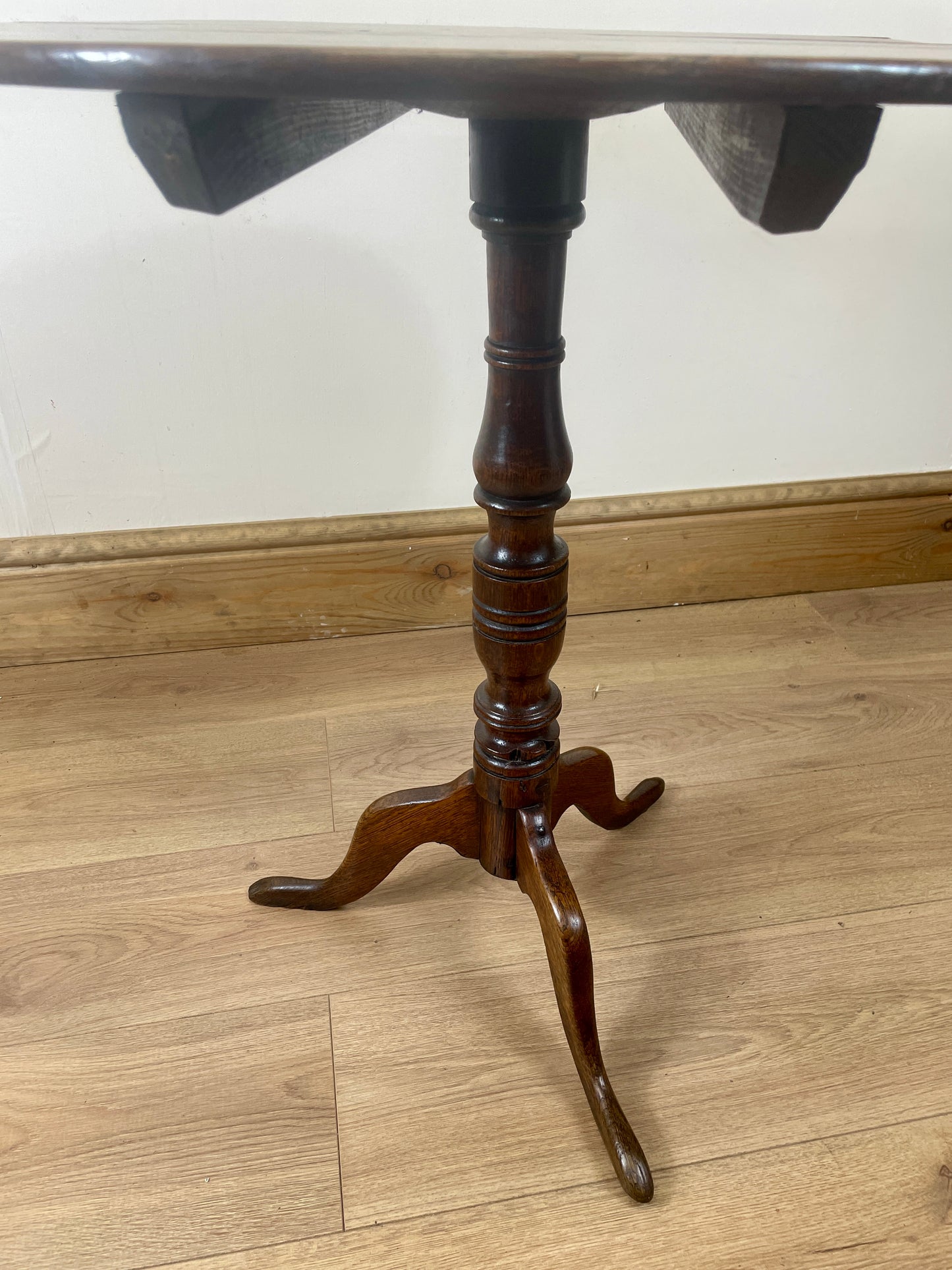 Wooden table with a tripod base on a wooden floor.
