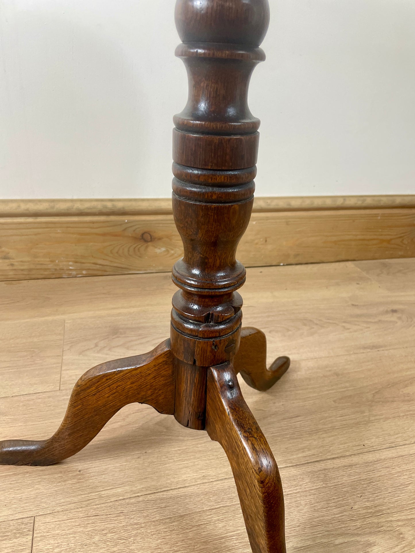 Wooden pedestal table base on a wooden floor