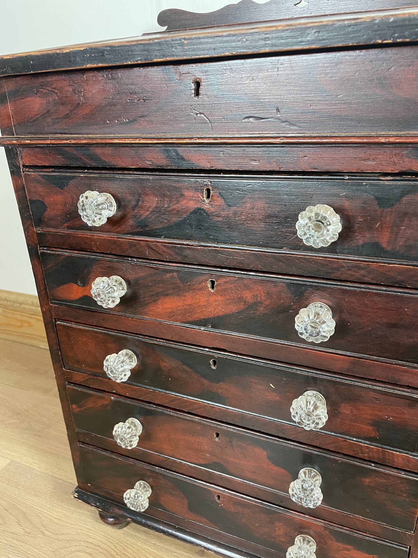 Wooden cabinet with glass knobs on a light wooden floor.