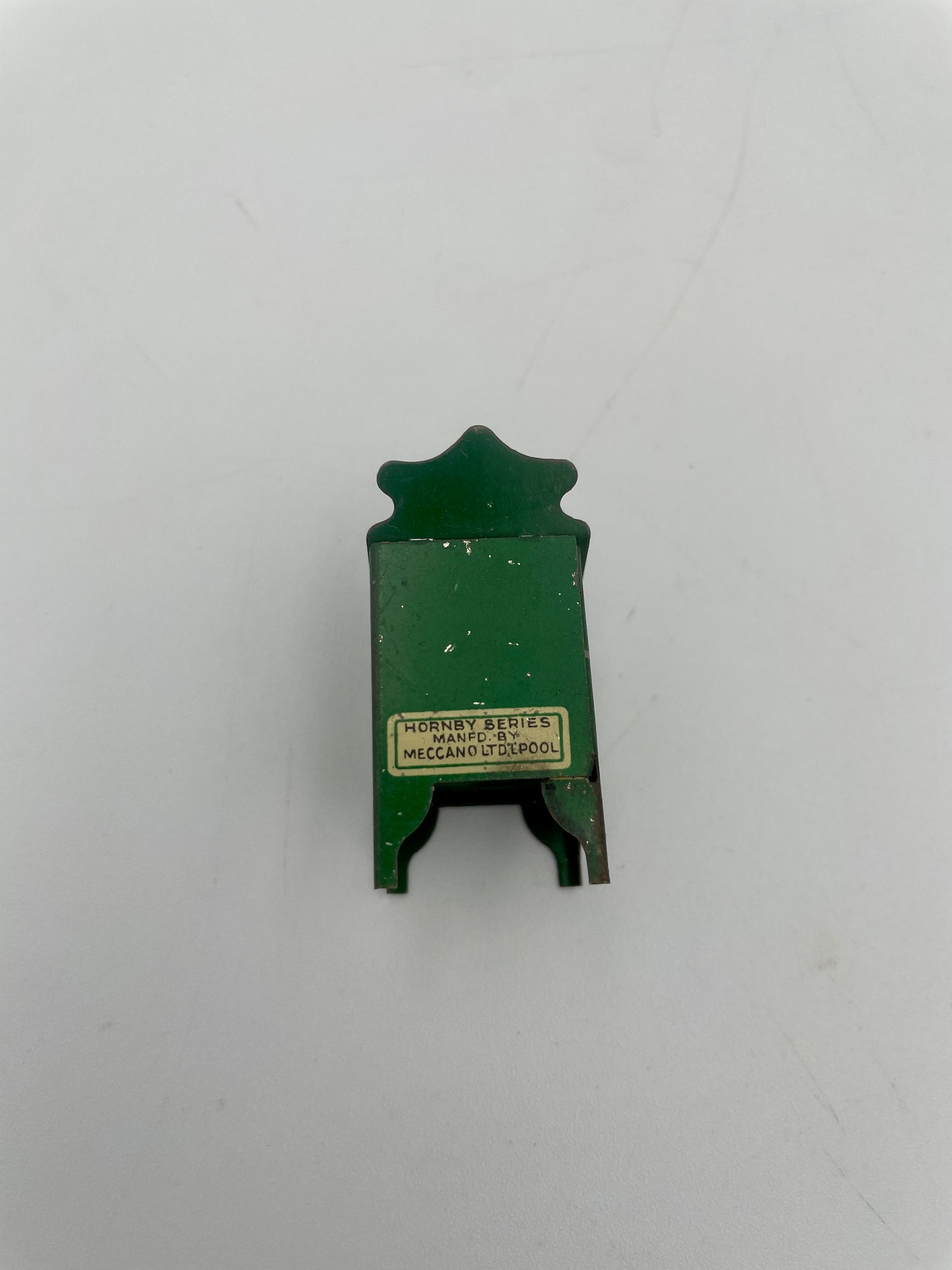 Green metal object with a label on a white background