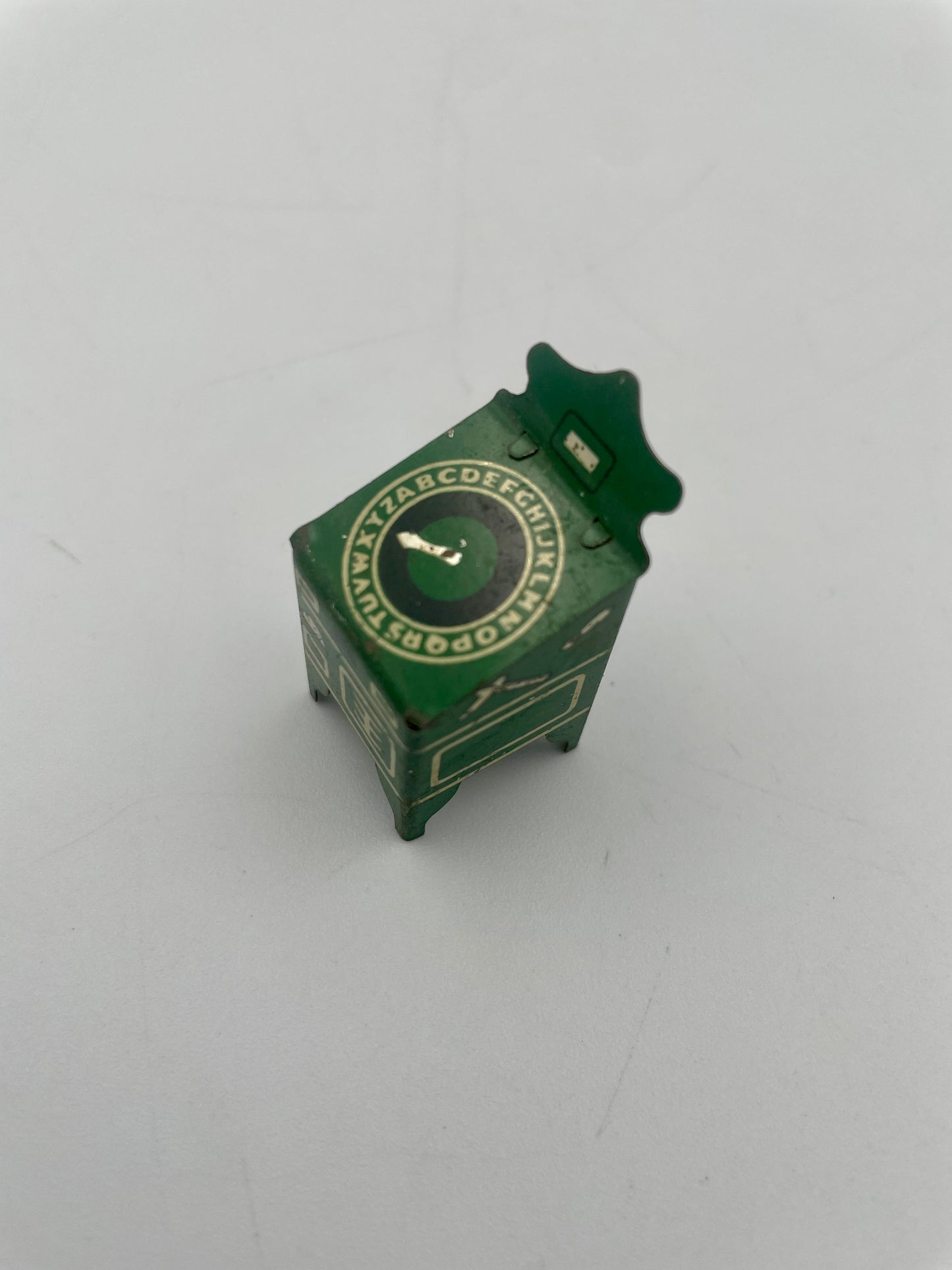 Small green toy cabinet with a clock face on a white background
