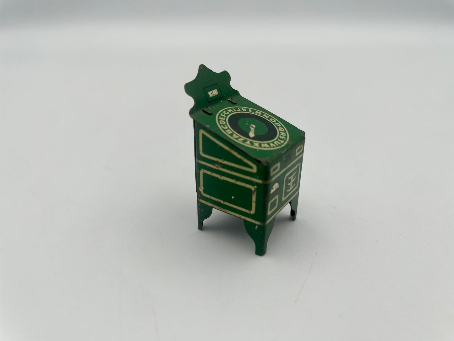 Small green model of a vintage clock on a white background