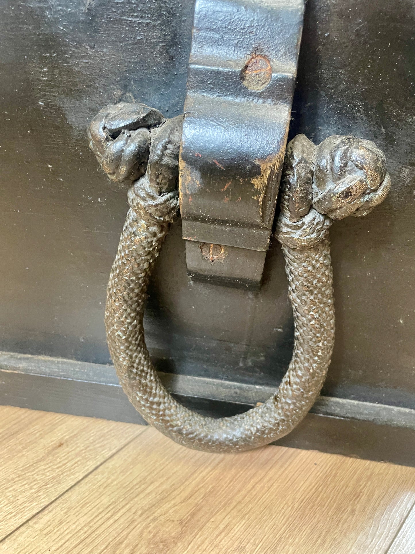 Decorative metal door knocker on a wooden floor