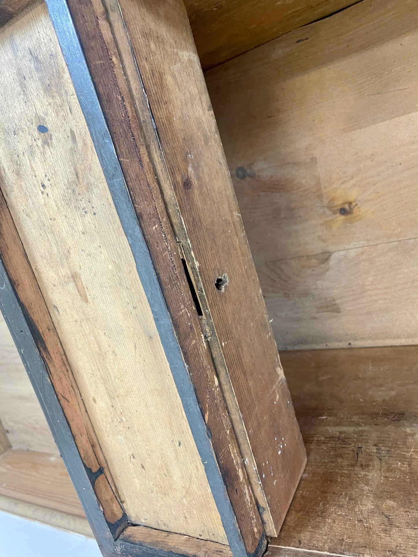 Close-up of a wooden cabinet with a metal hinge