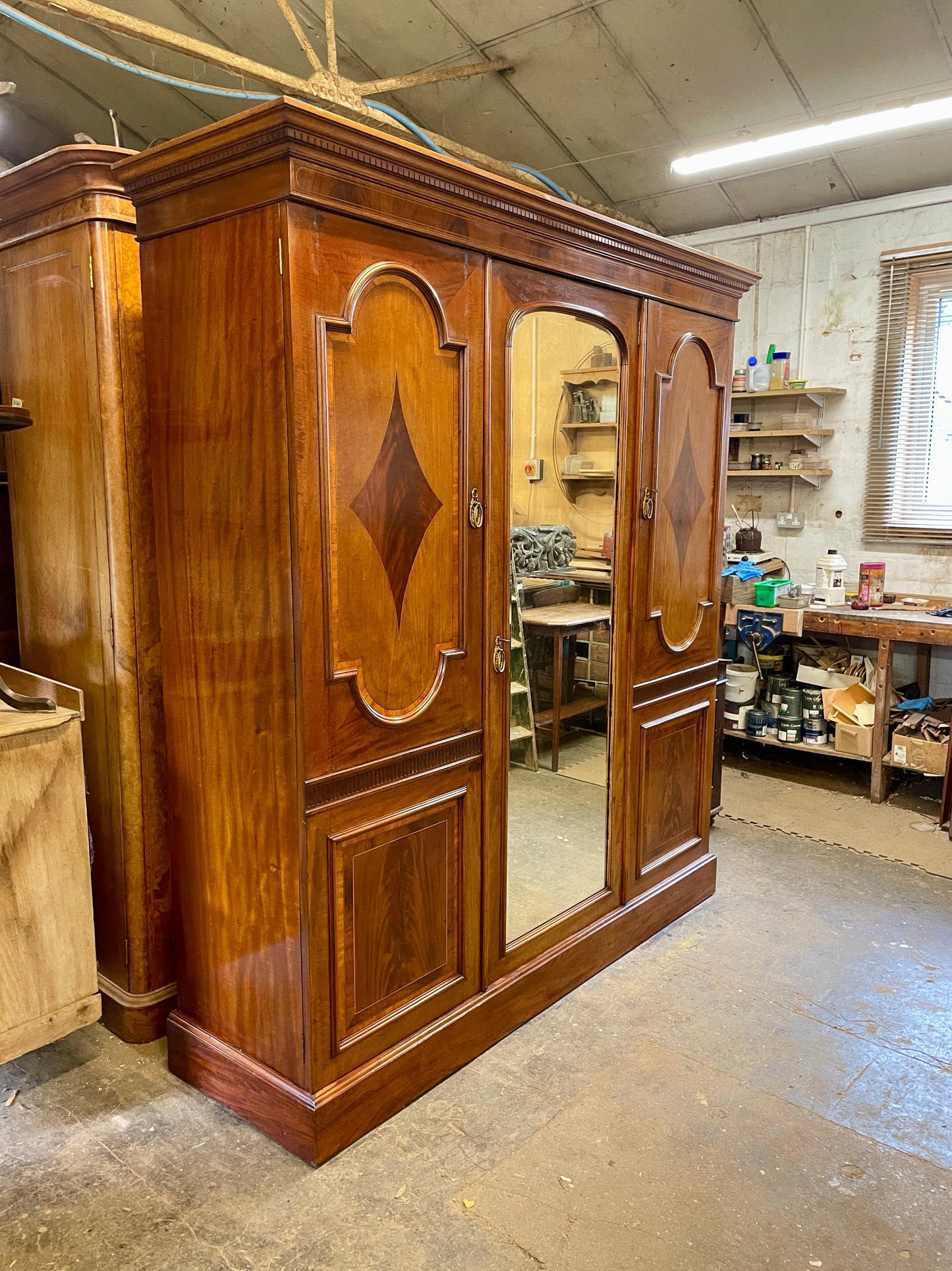 Large wooden wardrobe with mirror doors in a workshop setting