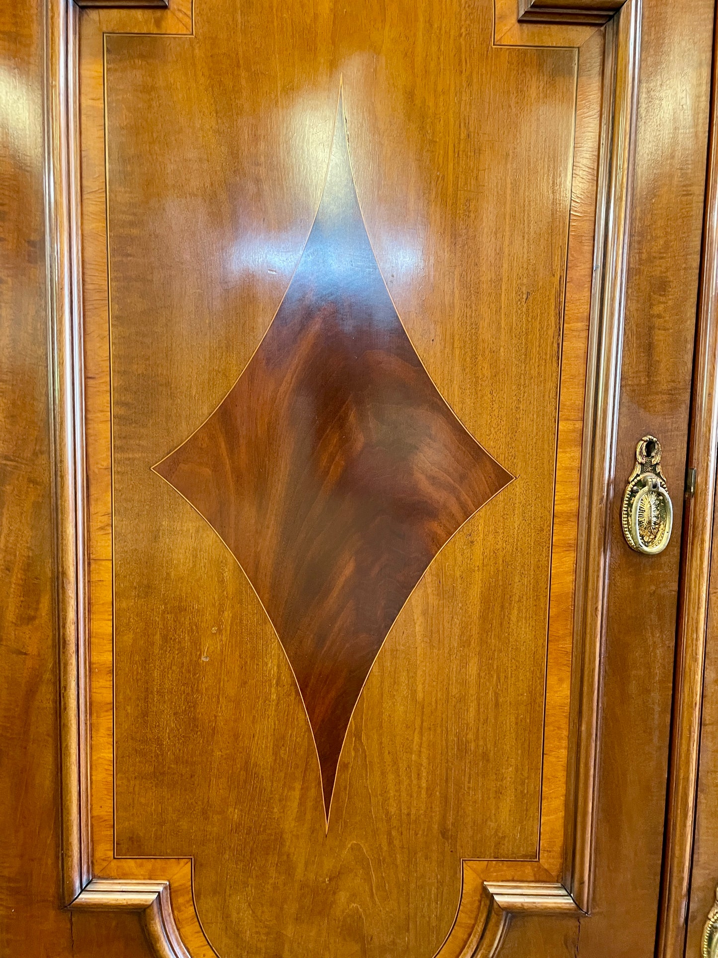 Close-up of a wooden door with decorative panel and brass knocker.