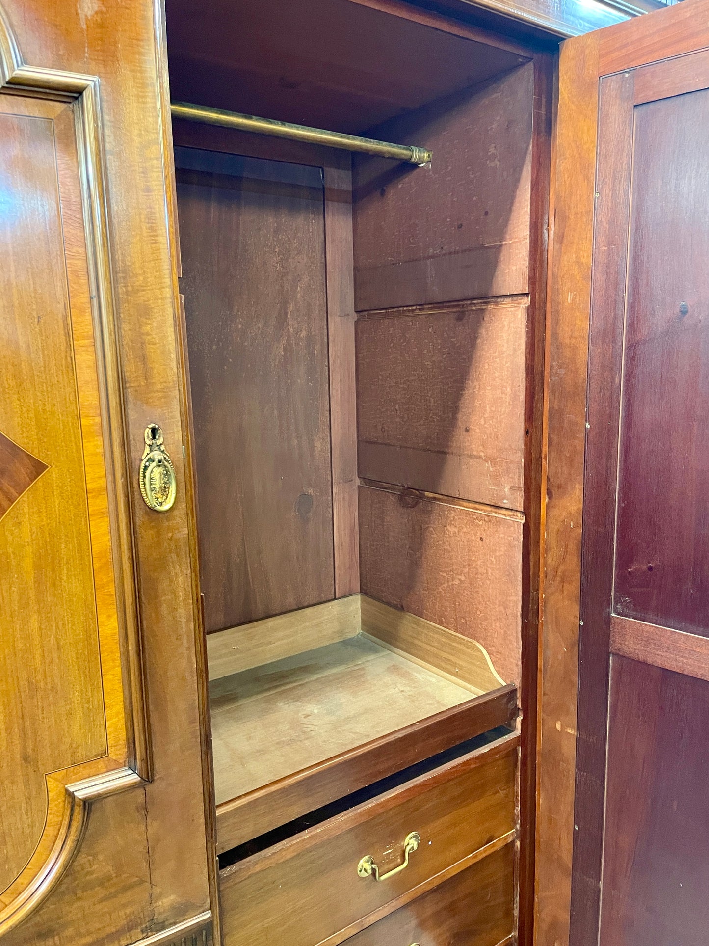 Wooden wardrobe with open doors showing shelves and drawers.