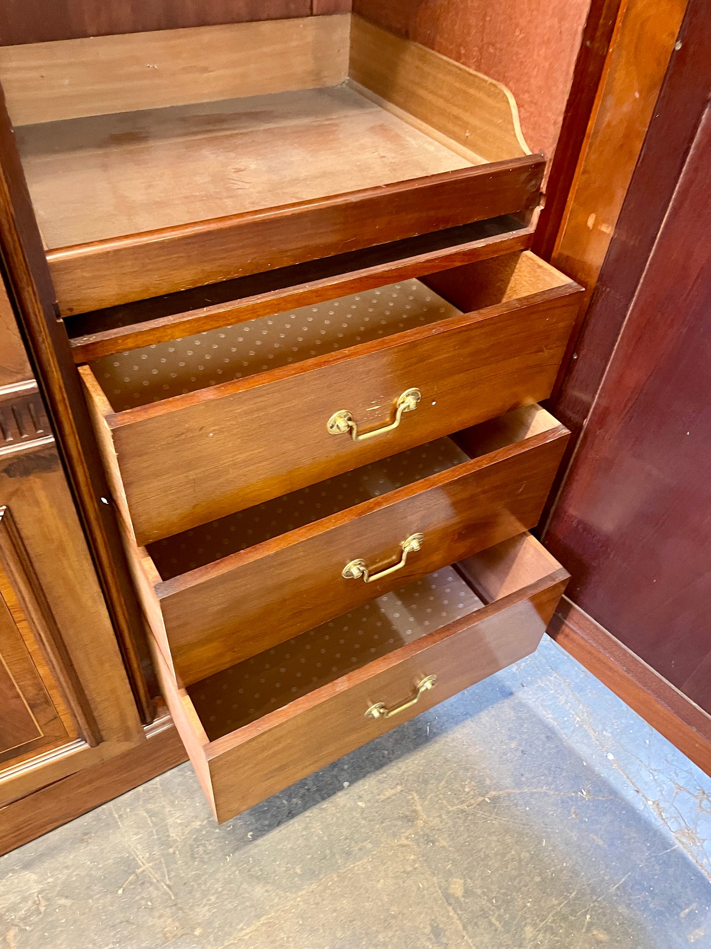Wooden dresser with open drawers on a concrete floor.