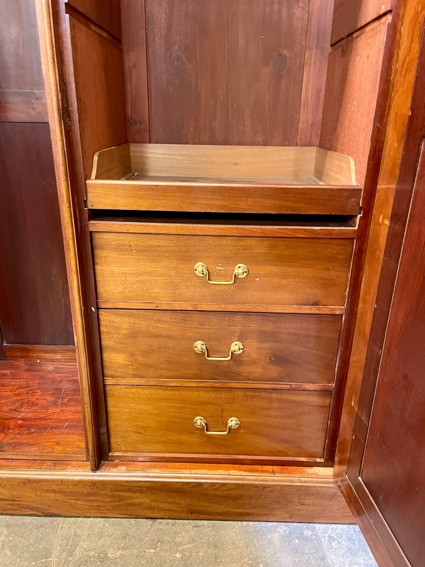 Wooden wardrobe with two drawers and brass handles on a wooden floor.