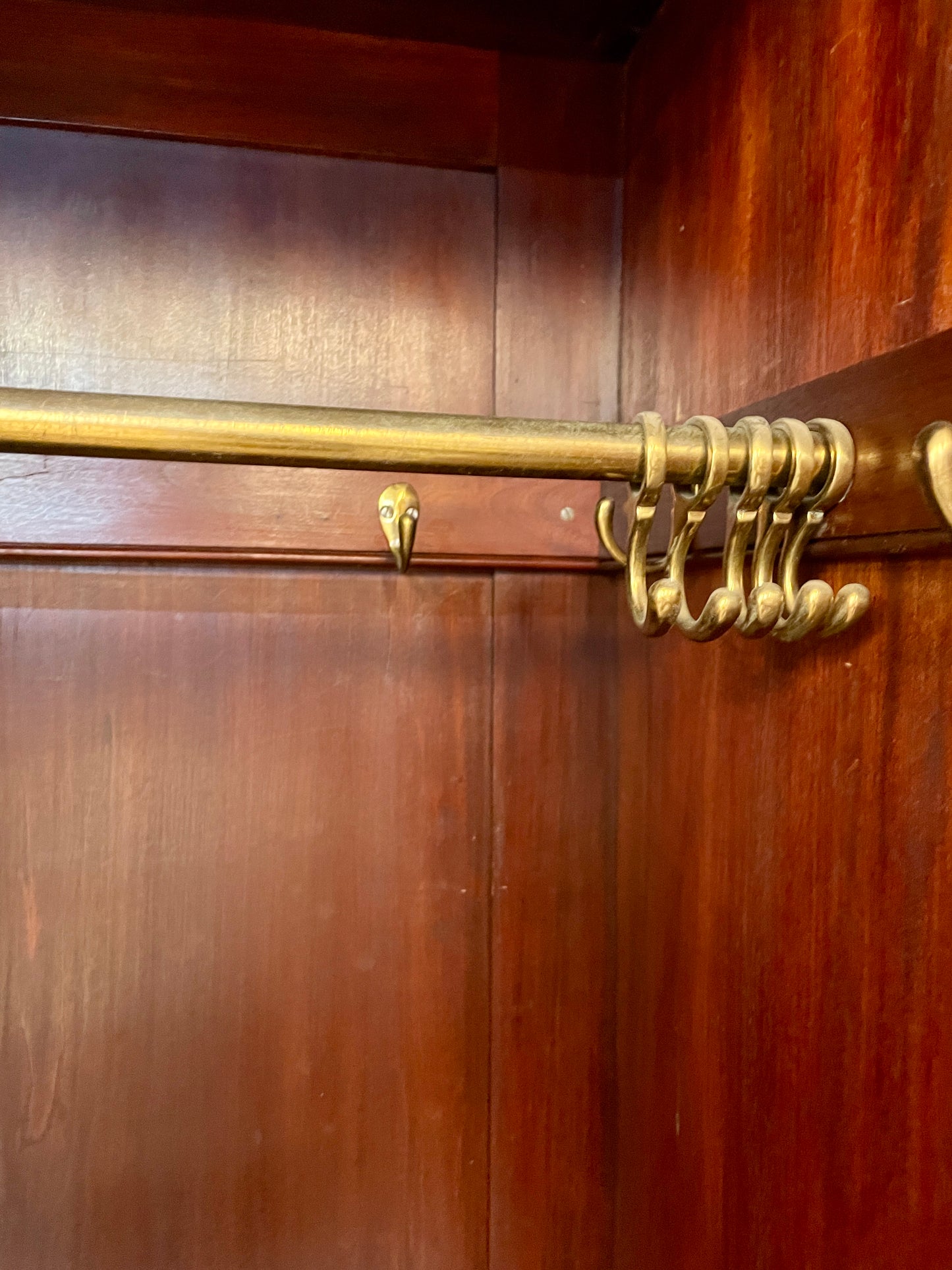 Brass rod with hooks on a wooden wardrobe