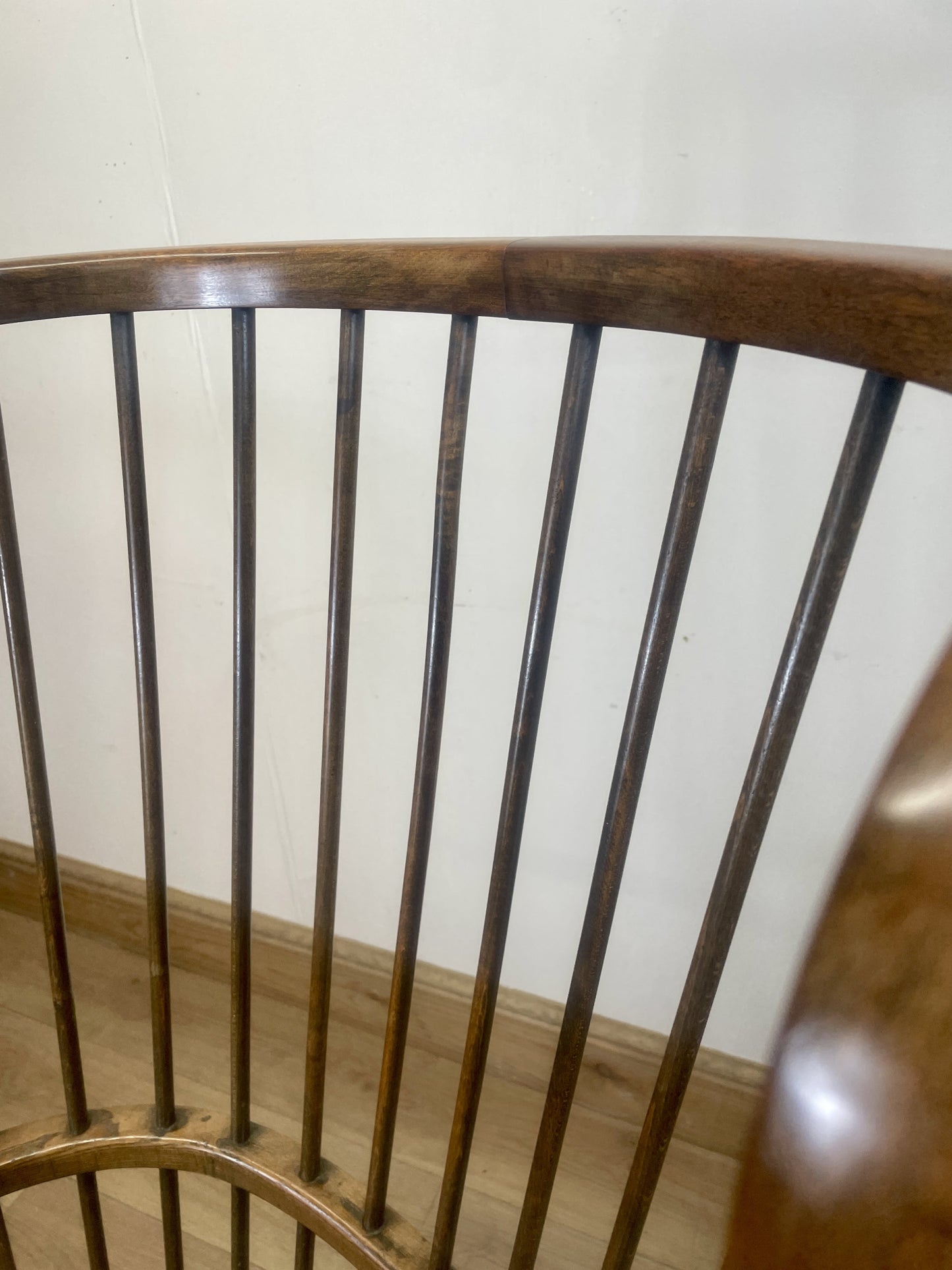 Wooden chair with slatted backrest against a white wall