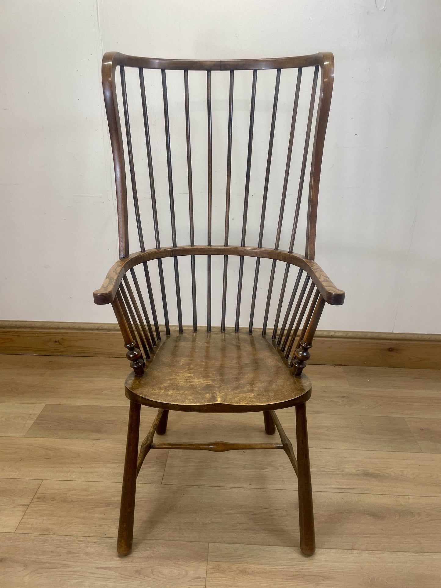 Wooden chair with spindle back on a wooden floor against a white wall