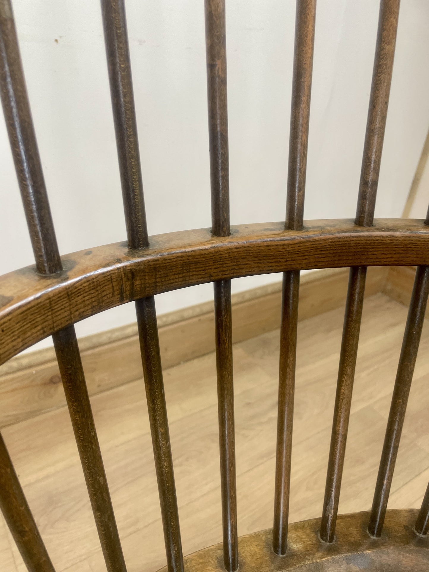 Close-up of a wooden chair with wooden legs on a light wood floor.