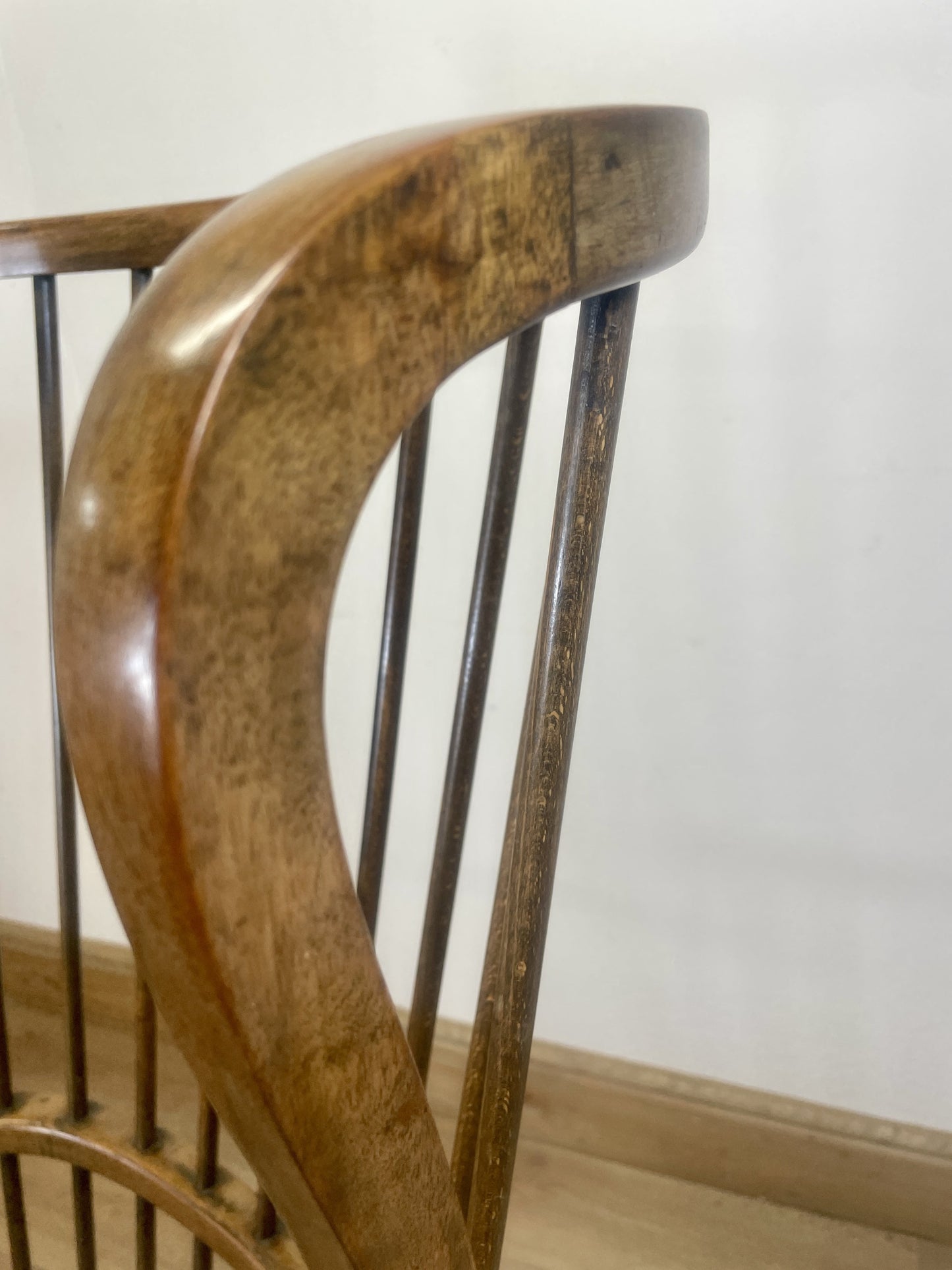 Wooden chair with curved backrest against a white wall