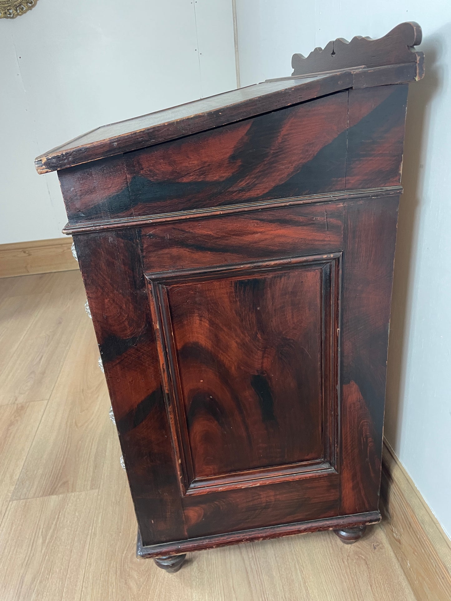 Wooden cabinet with a dark finish on a light wooden floor.