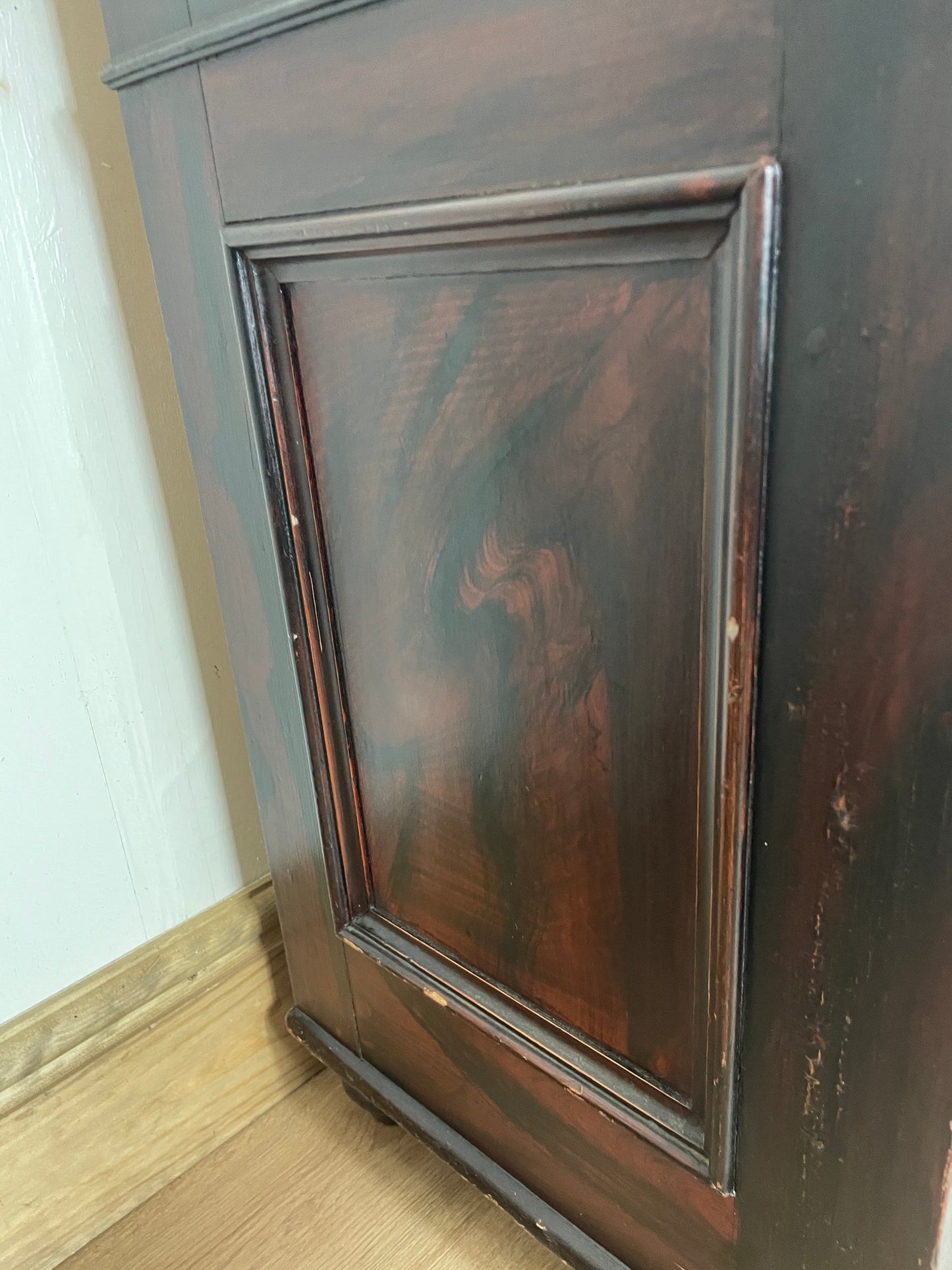 Wooden cabinet with a glass panel on a white and wooden floor.