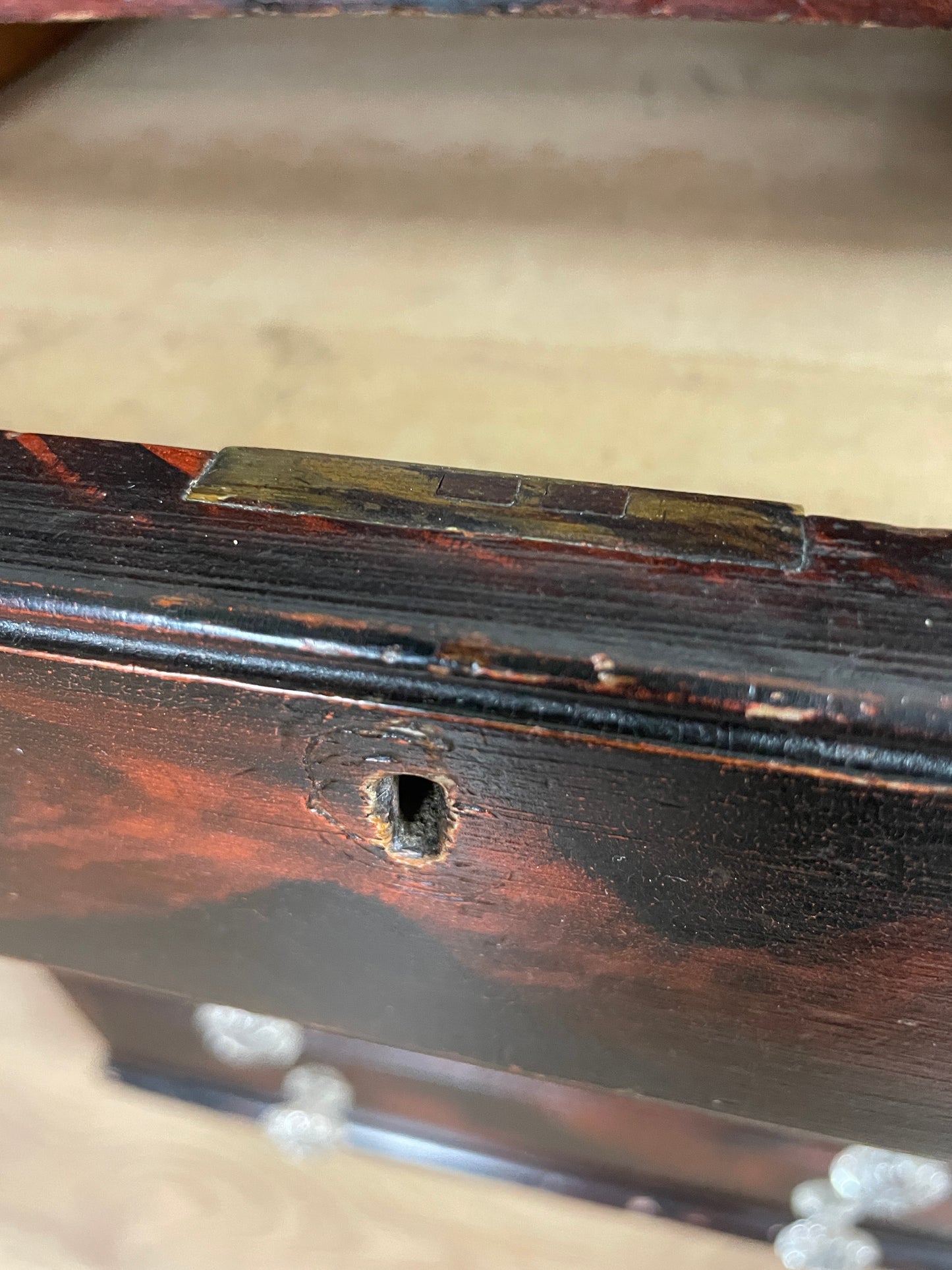Close-up of a wooden surface with a small hole and surrounding wear.