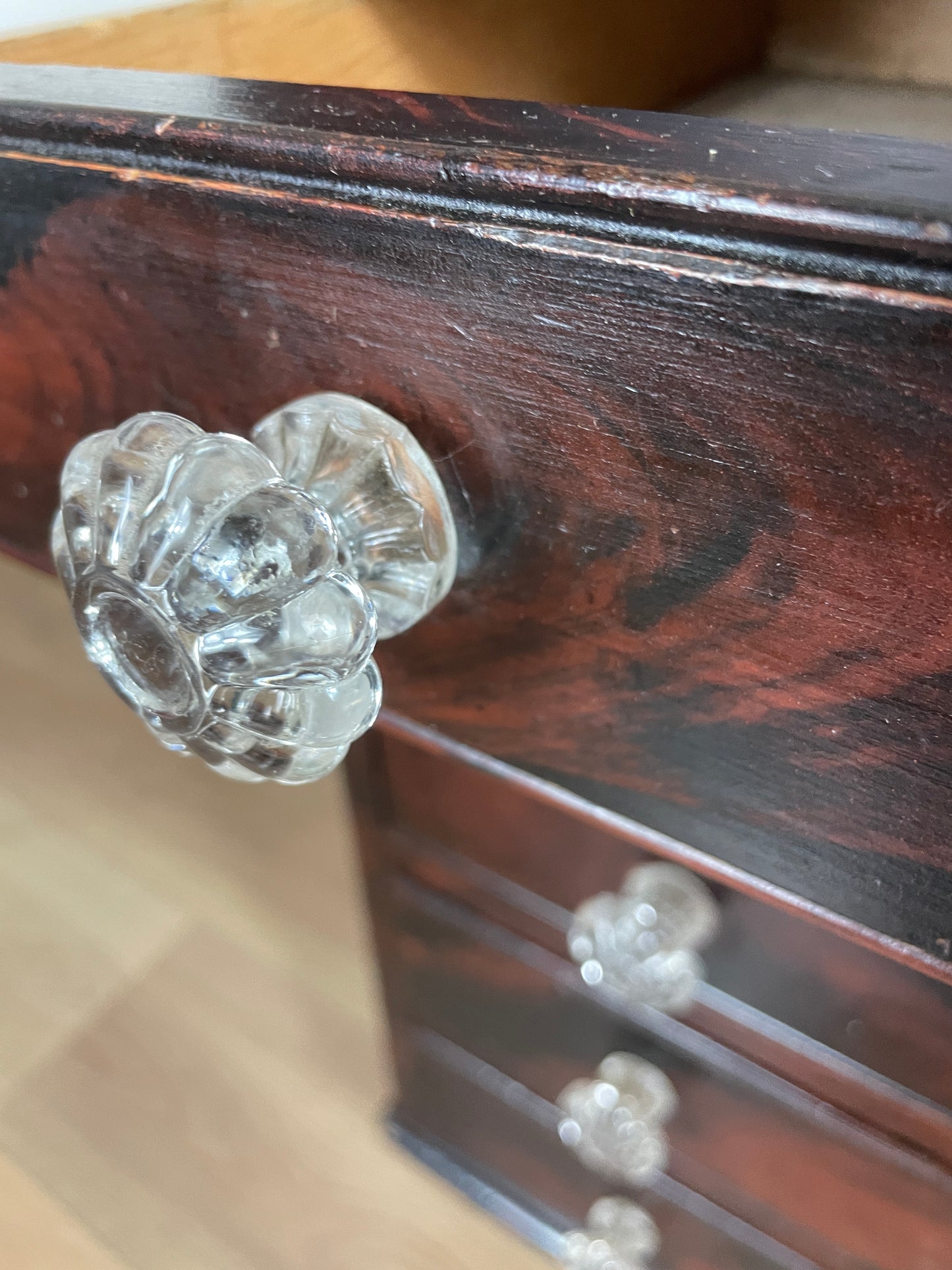 Close-up of a wooden cabinet with glass knobs on a blurred background