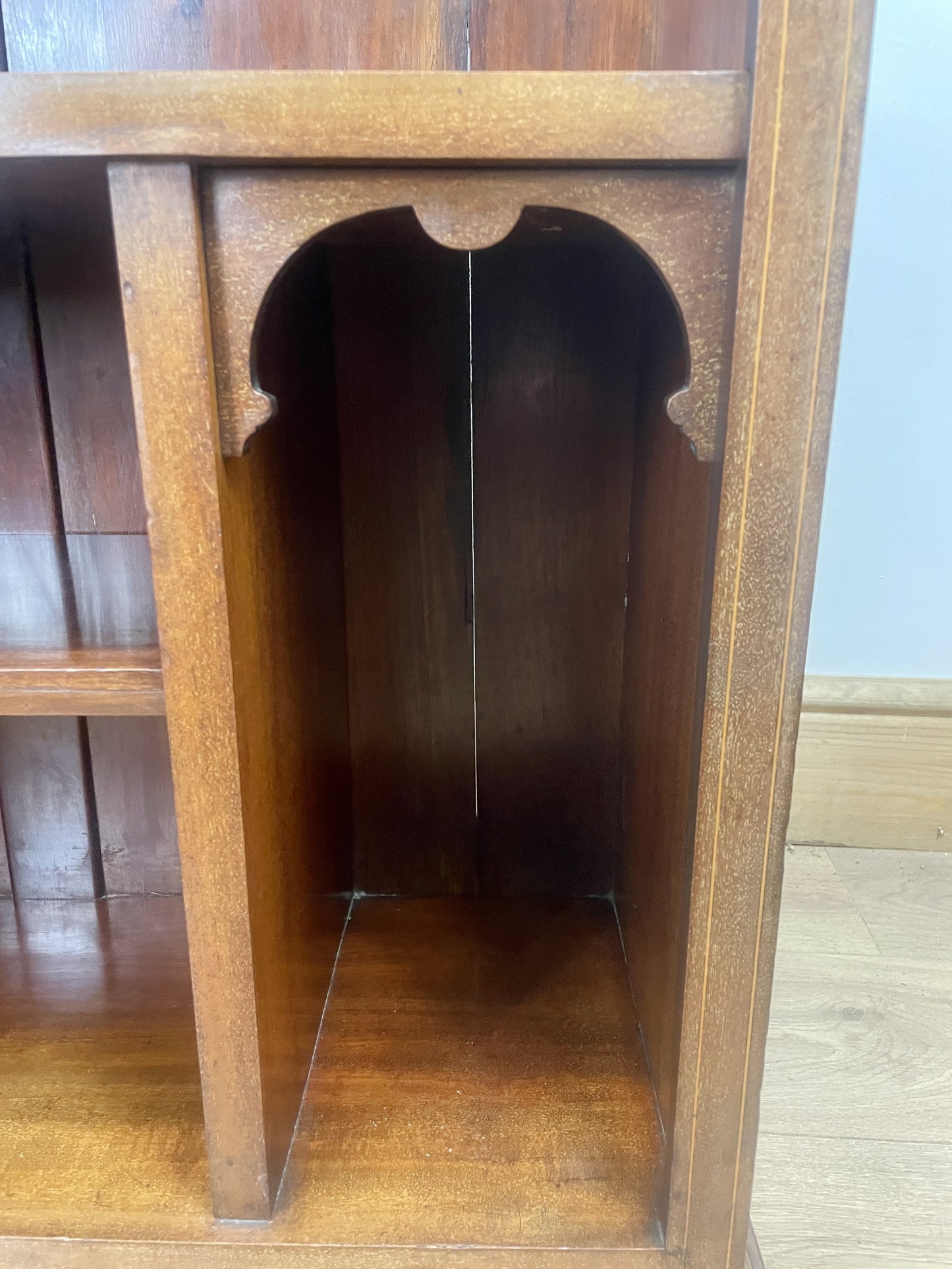 Wooden shelf with decorative cutout design on a wooden floor.