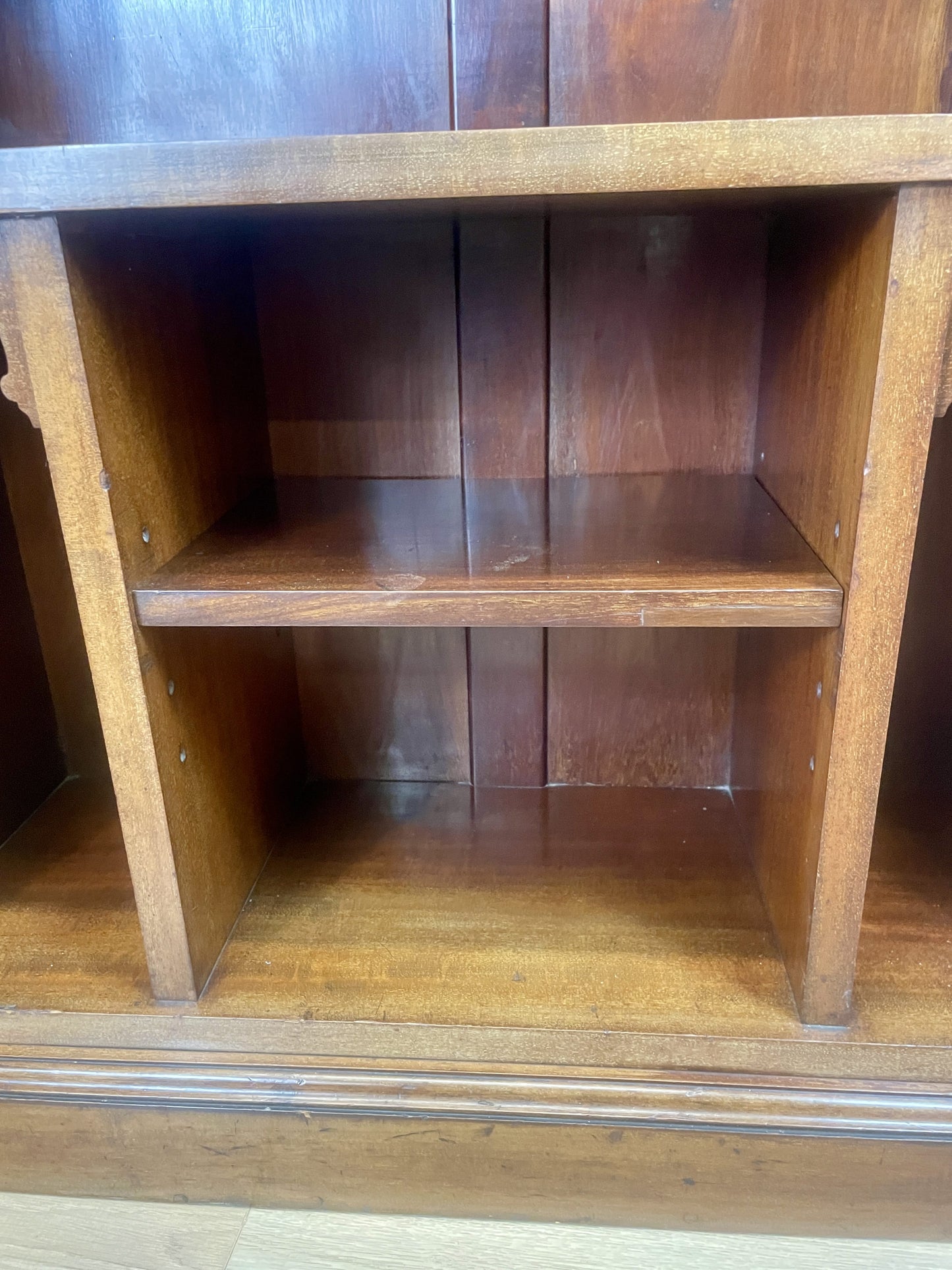 Wooden bookshelf with two shelves against a wooden wall.