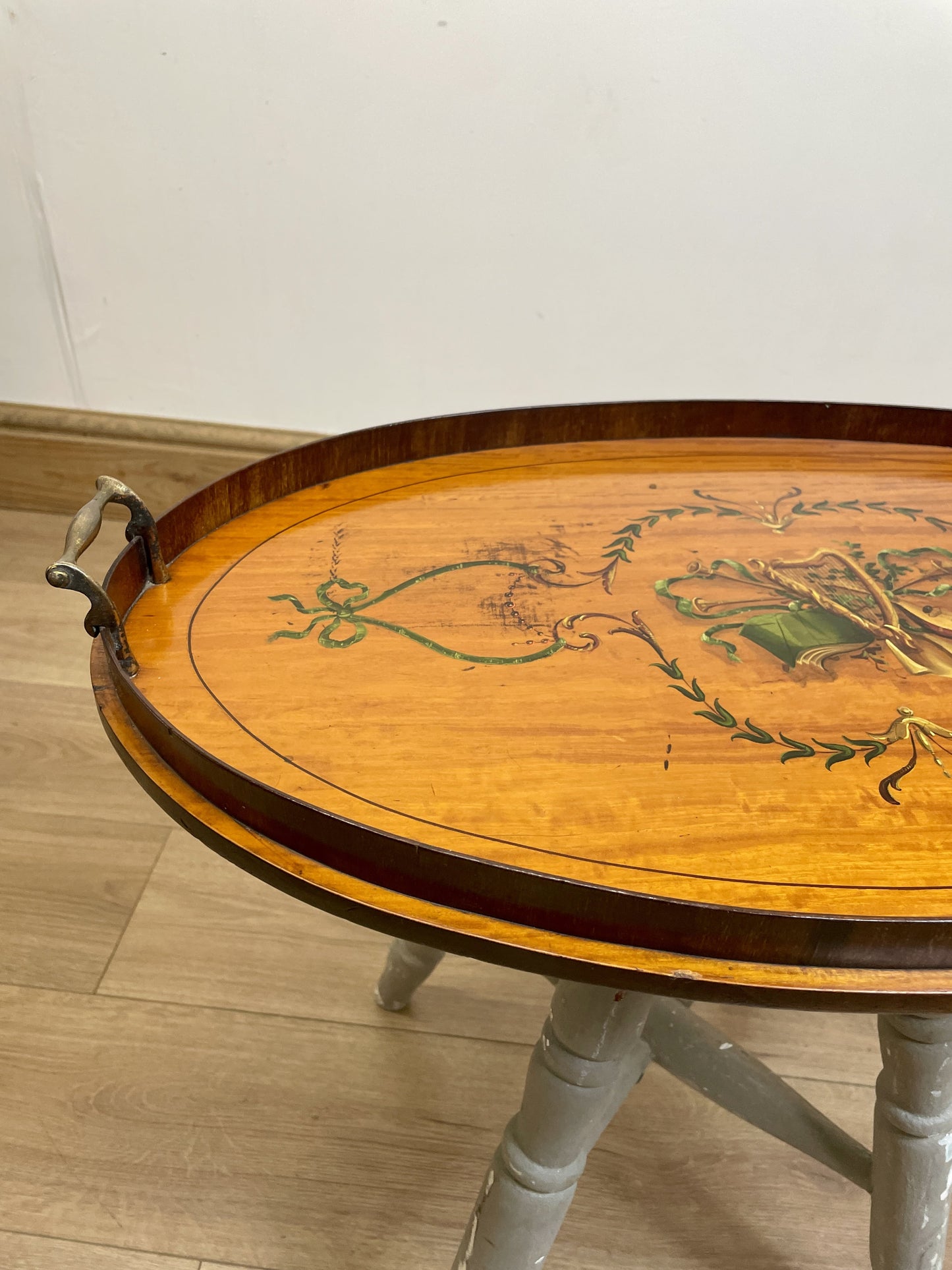 Round wooden table with floral designs on a light wood floor.