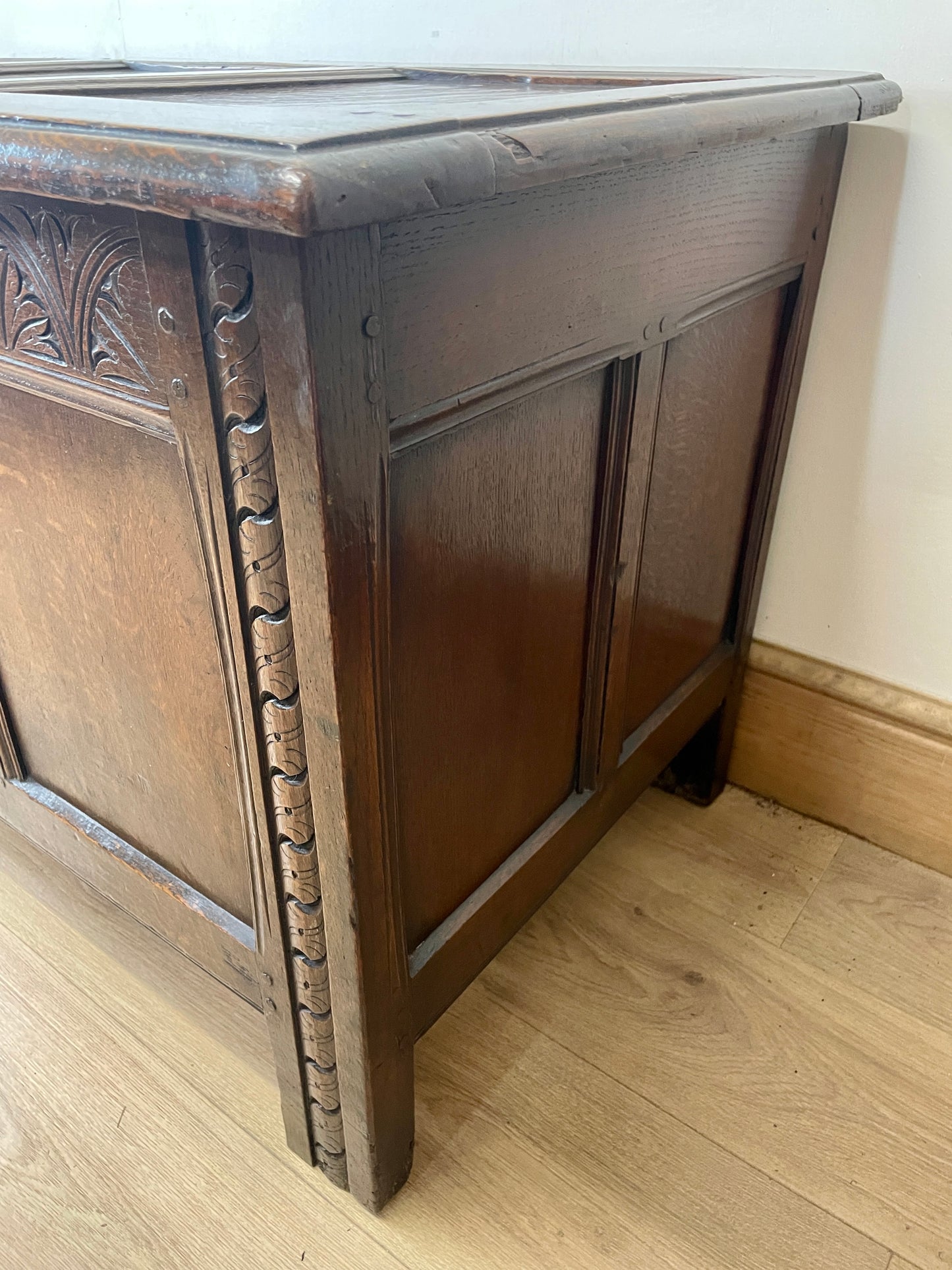 Wooden coffer with intricate carvings on a wooden floor.