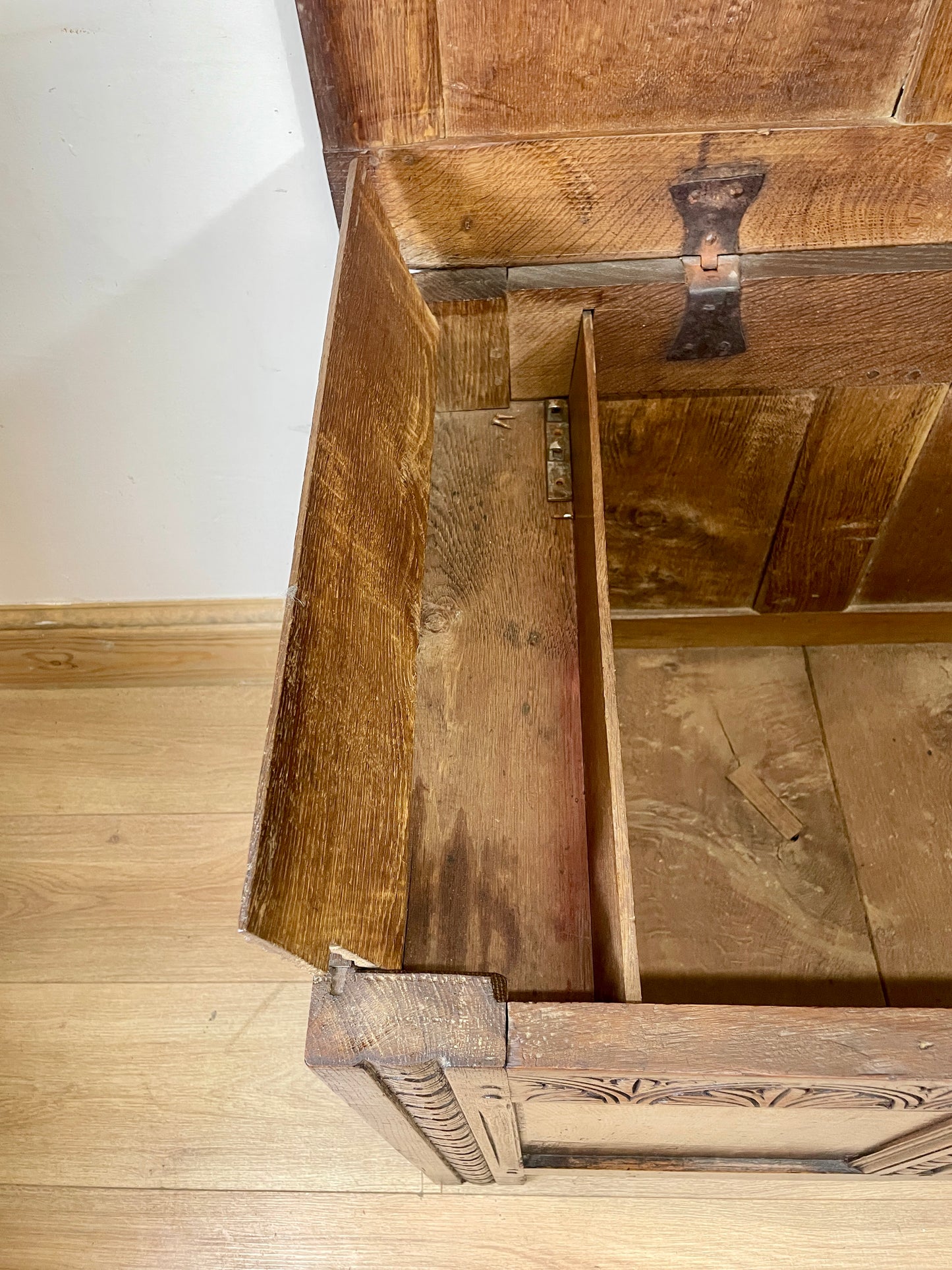 Wooden drawer with a visible hinge on a wooden floor.