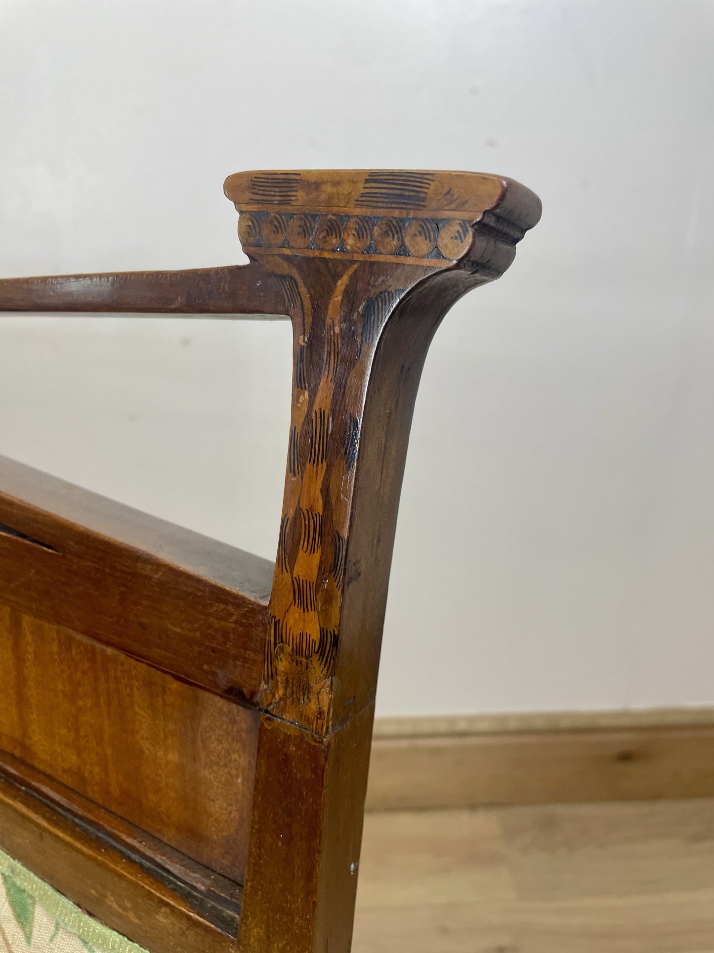 Close-up of a wooden chair arm with a white wall background