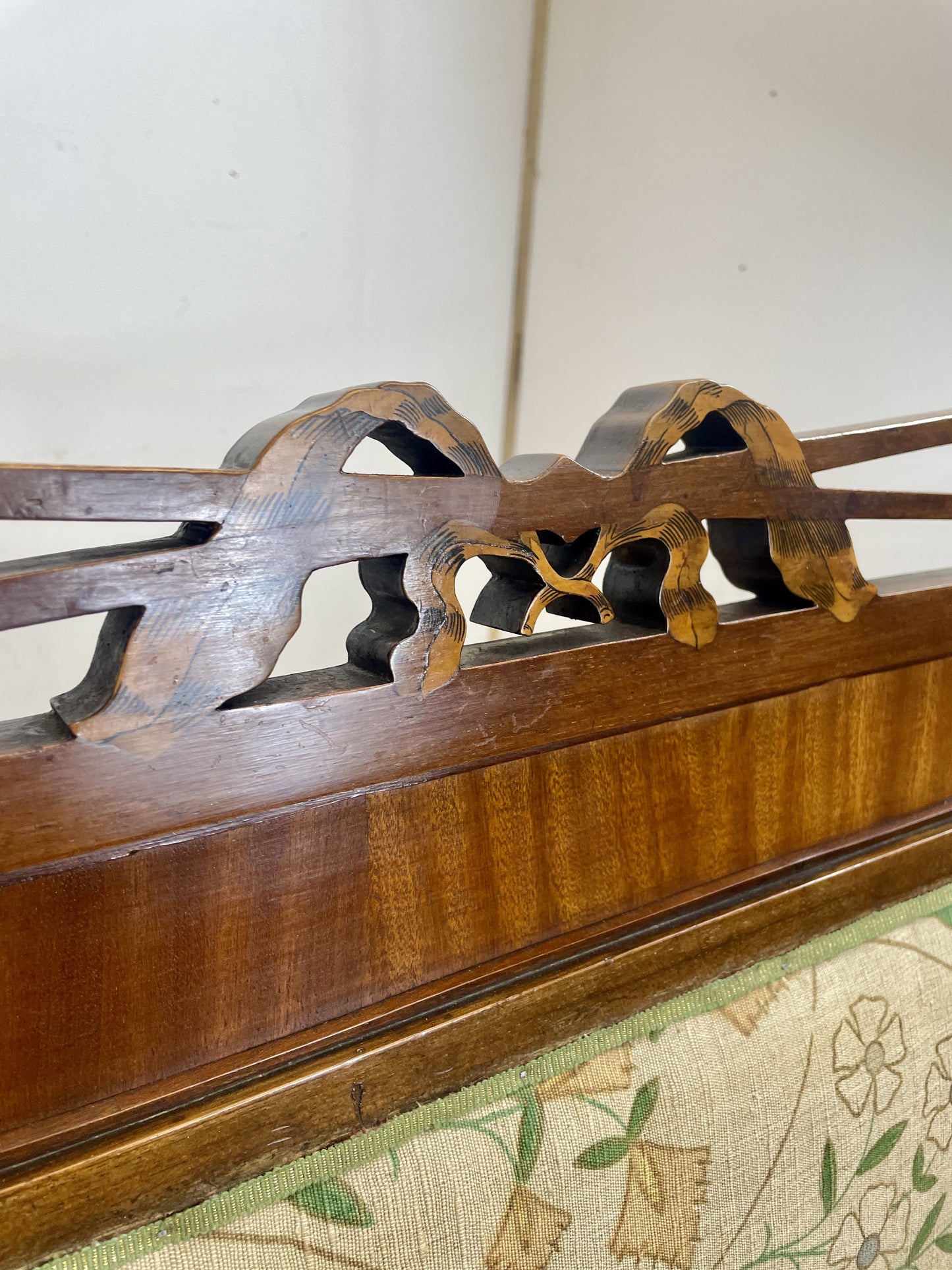 Wooden bow holder with decorative carvings on a floral-patterned surface.