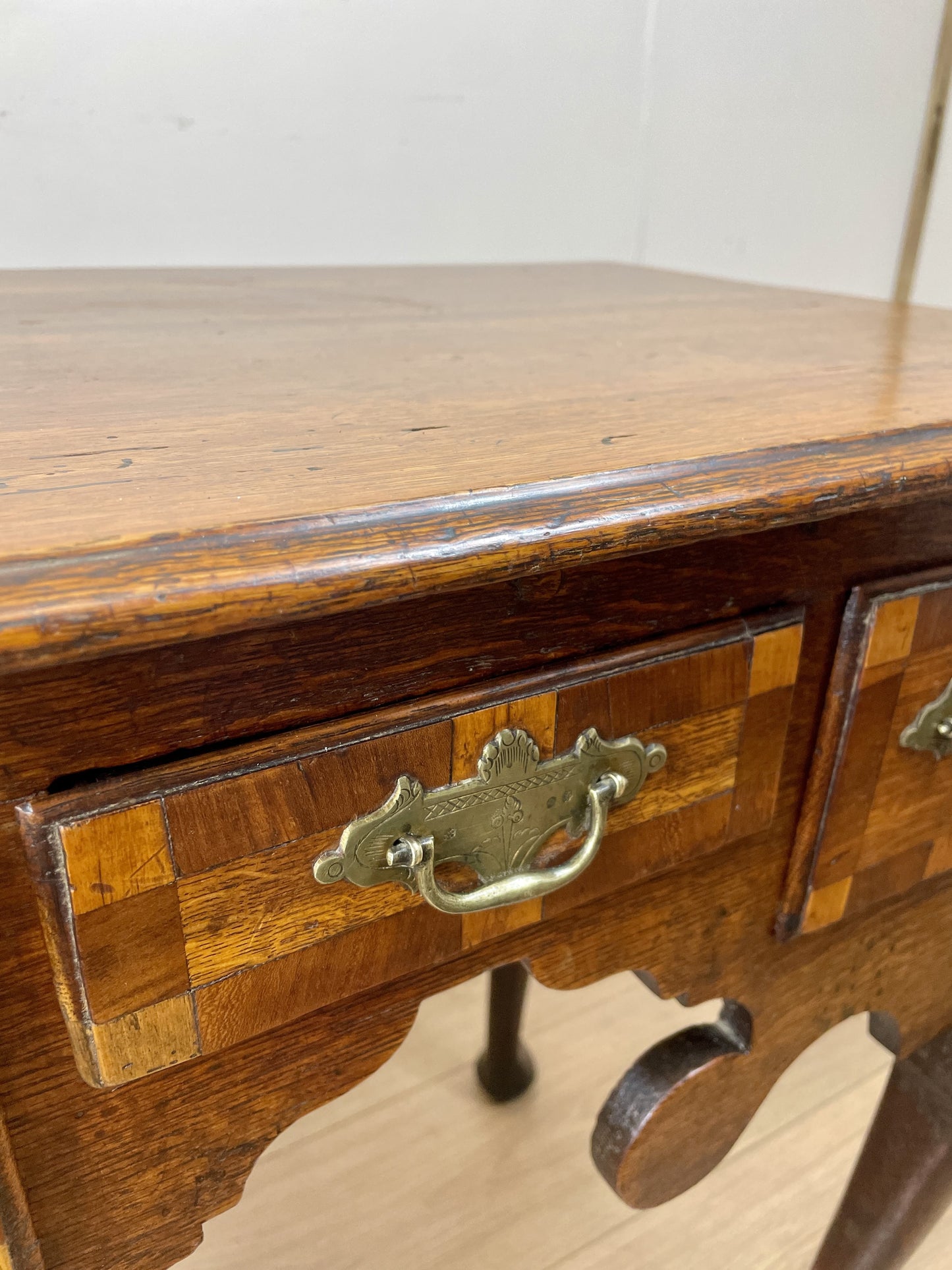 Wooden drawer with decorative inlay and brass handle on a white background