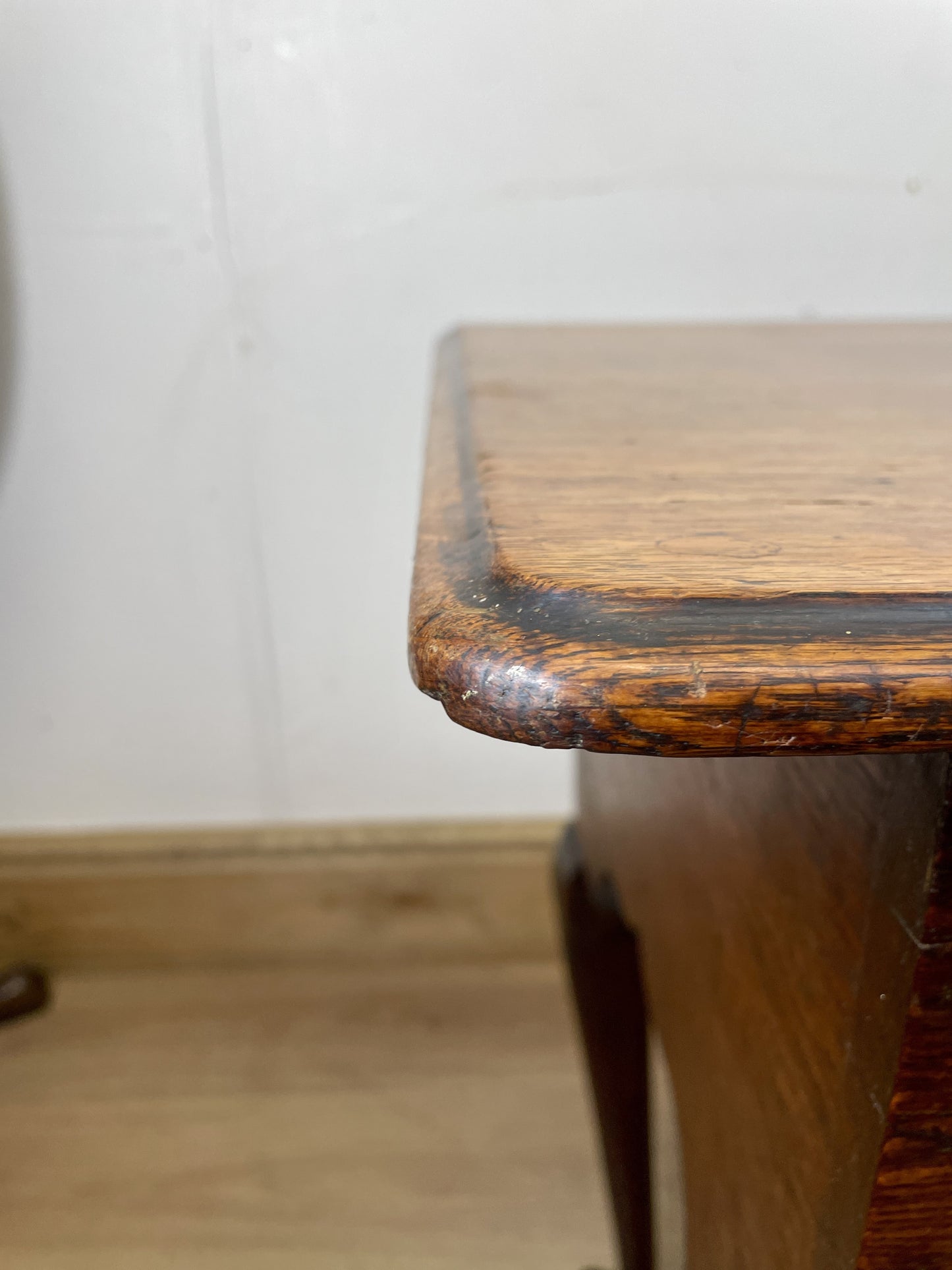 Wooden stool with a worn surface against a white wall