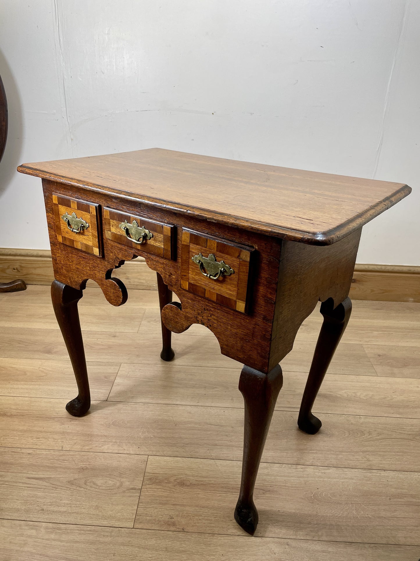 Wooden side table with four drawers on a wooden floor.