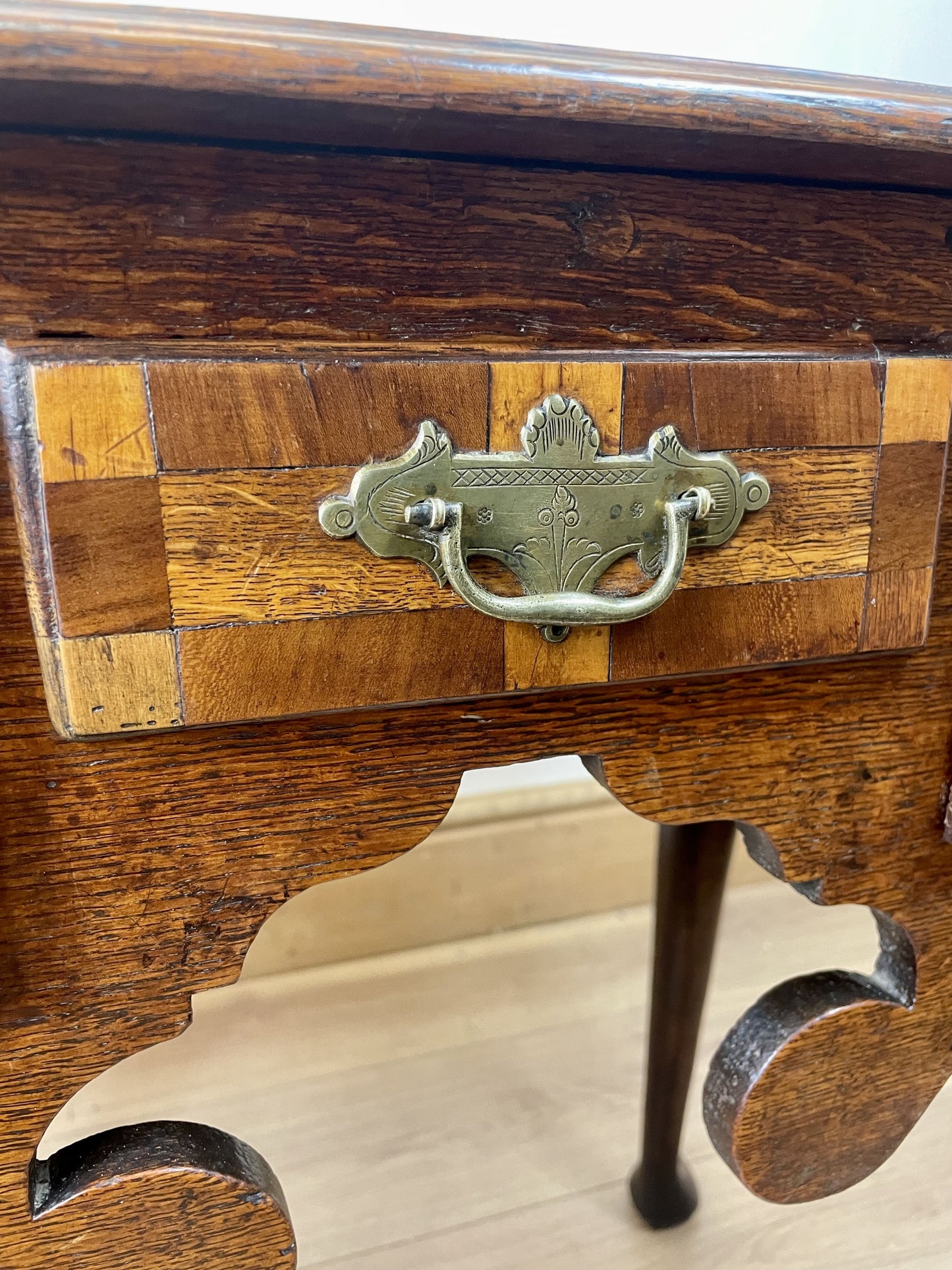 Close-up of a wooden desk with a metal handle on a white surface