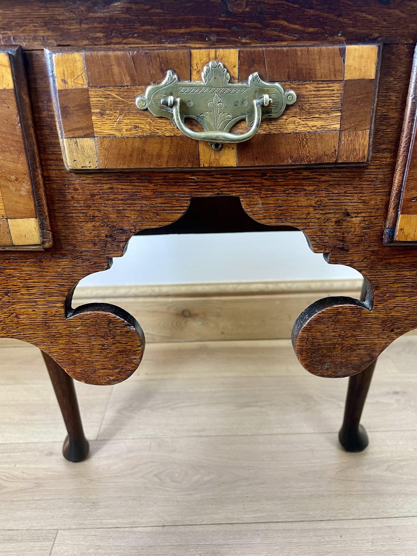 Wooden desk with a checkered pattern and metal handle on a wooden floor.