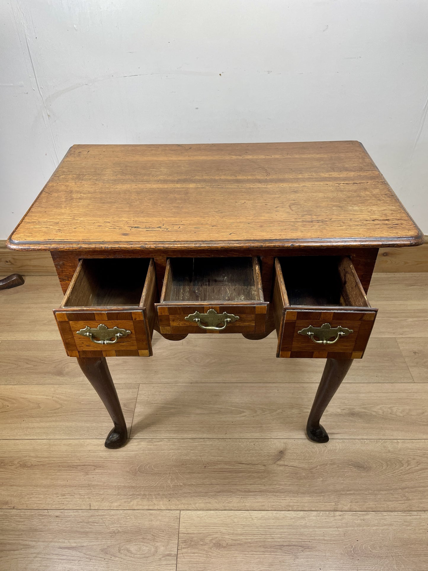 Wooden desk with three drawers on a wooden floor.