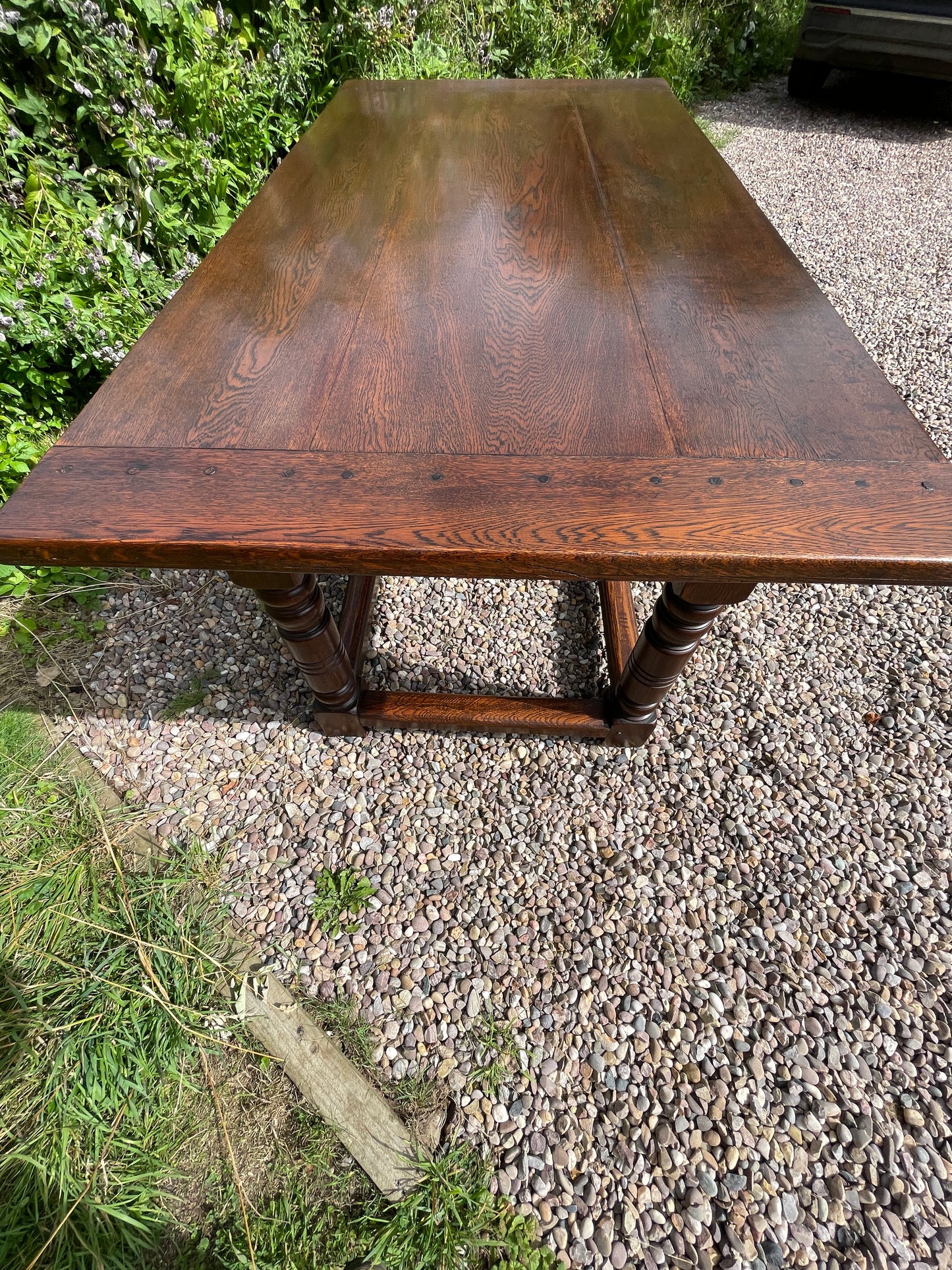 Wooden table on a gravel surface with grass and plants around