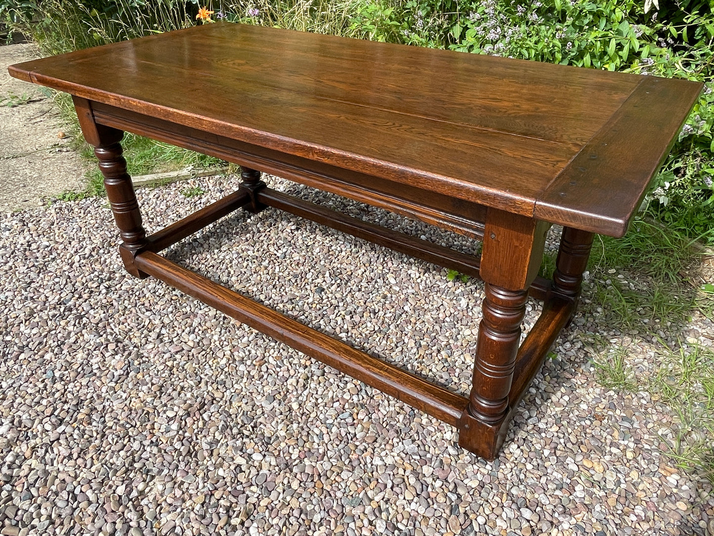 Wooden table with a rustic design on a gravel surface with grass in the background
