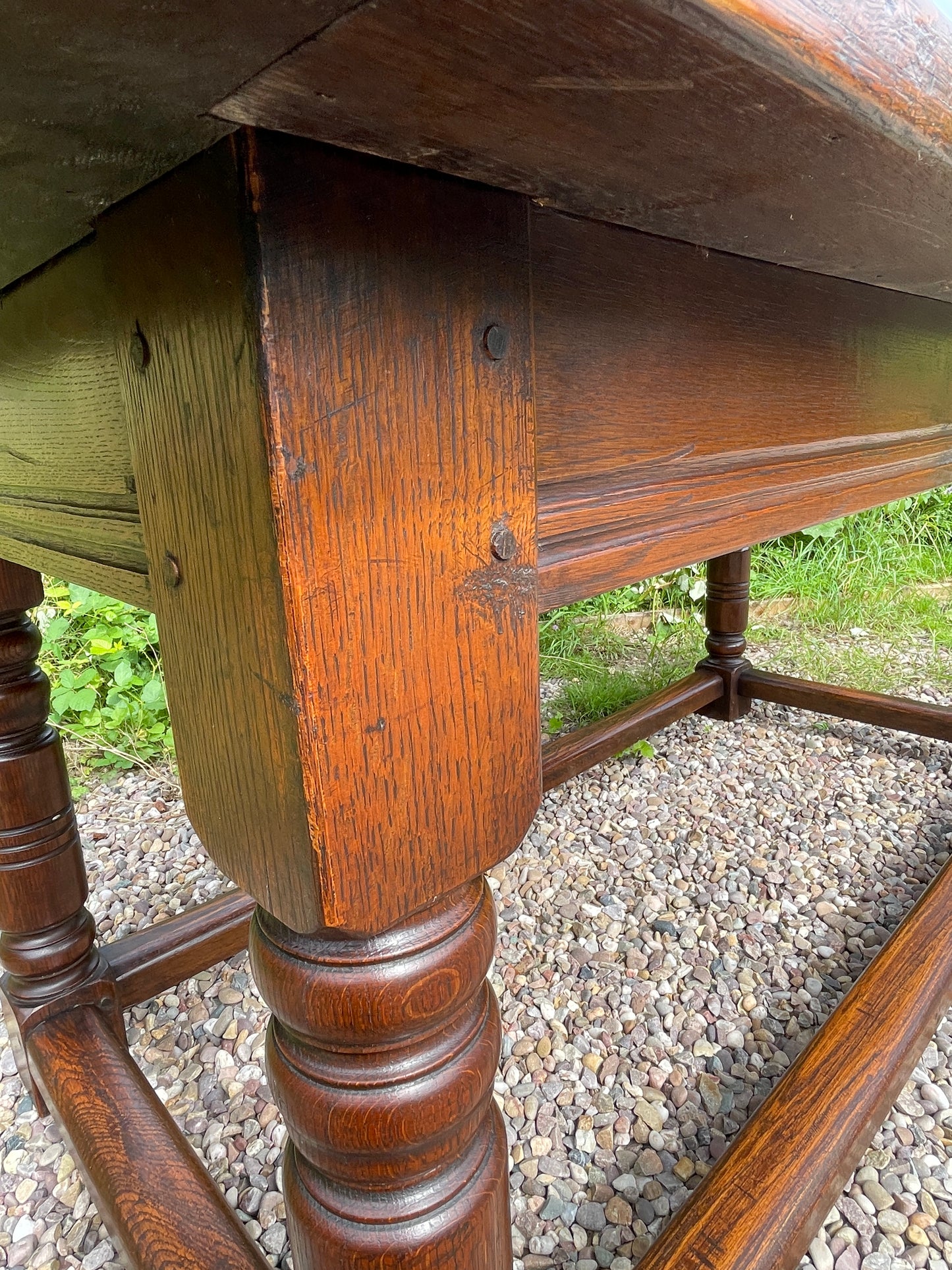 Close-up of a wooden table with visible grain and wear on a gravel surface.