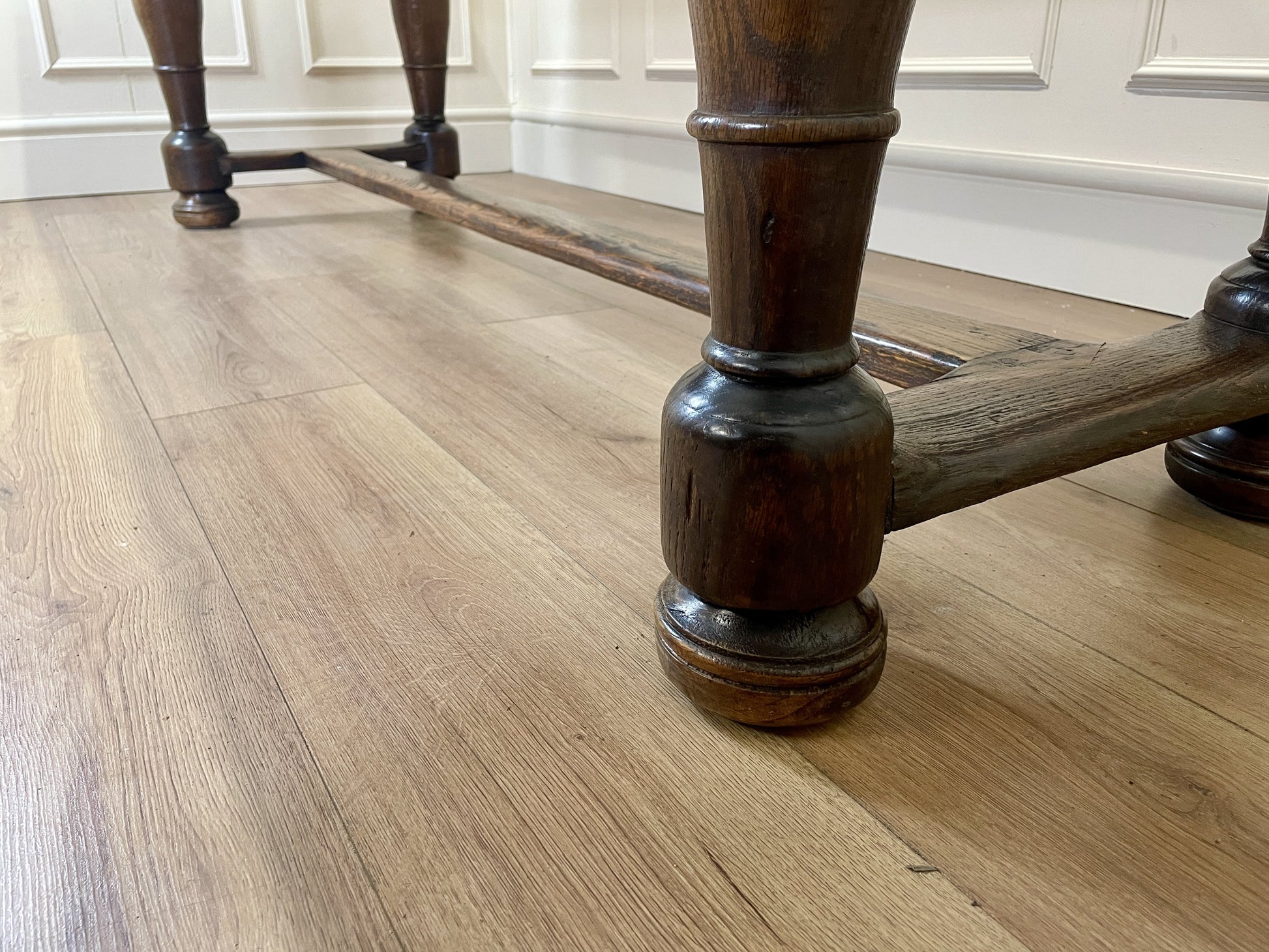 Wooden chair legs on a wooden floor with white cabinets in the background