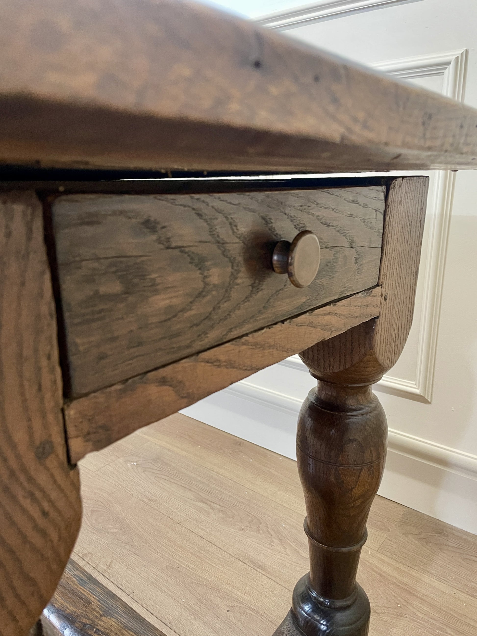 Wooden table with a drawer and knob on a wooden floor.