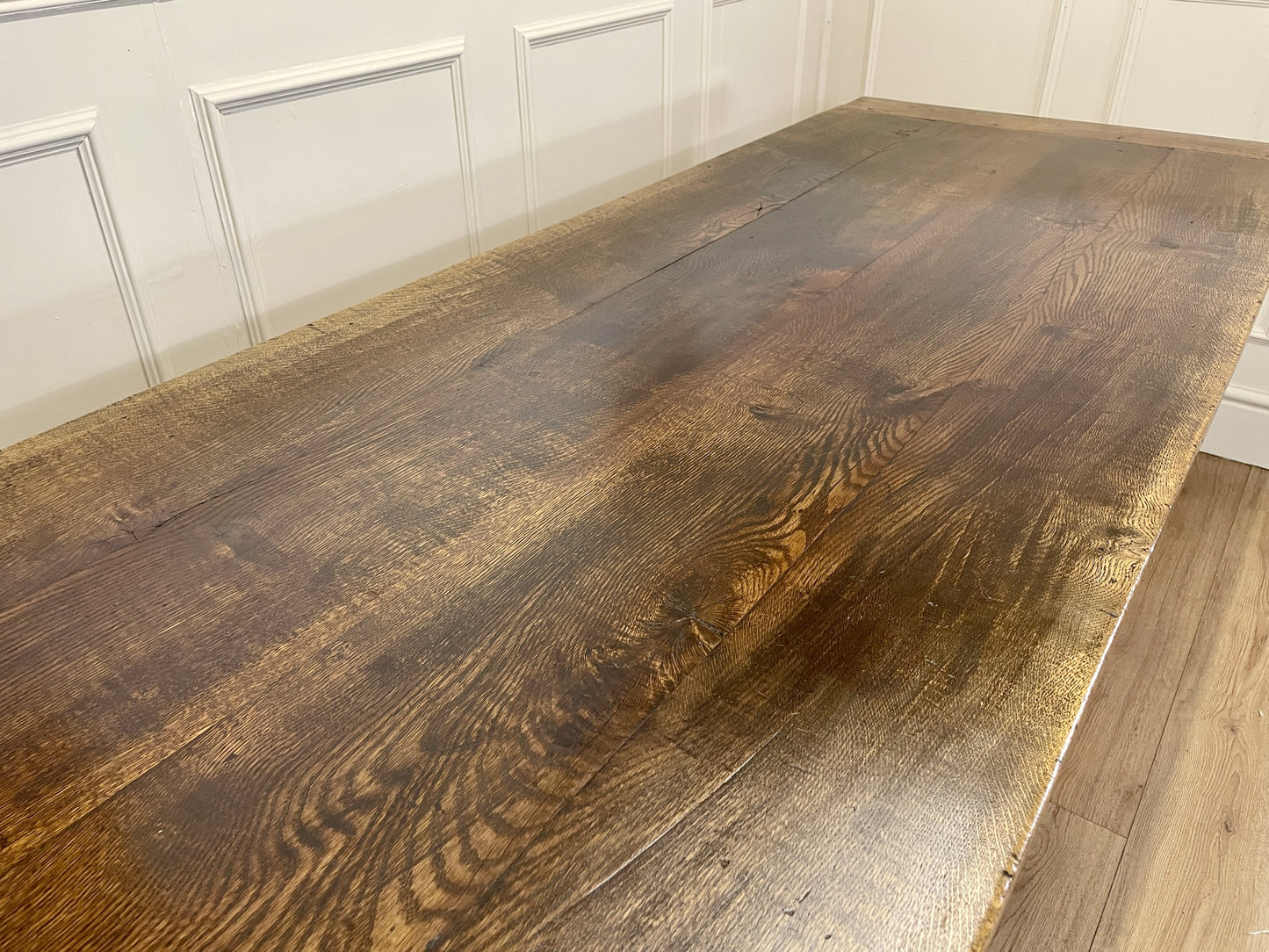 Wooden table with a dark finish against a white paneled wall.