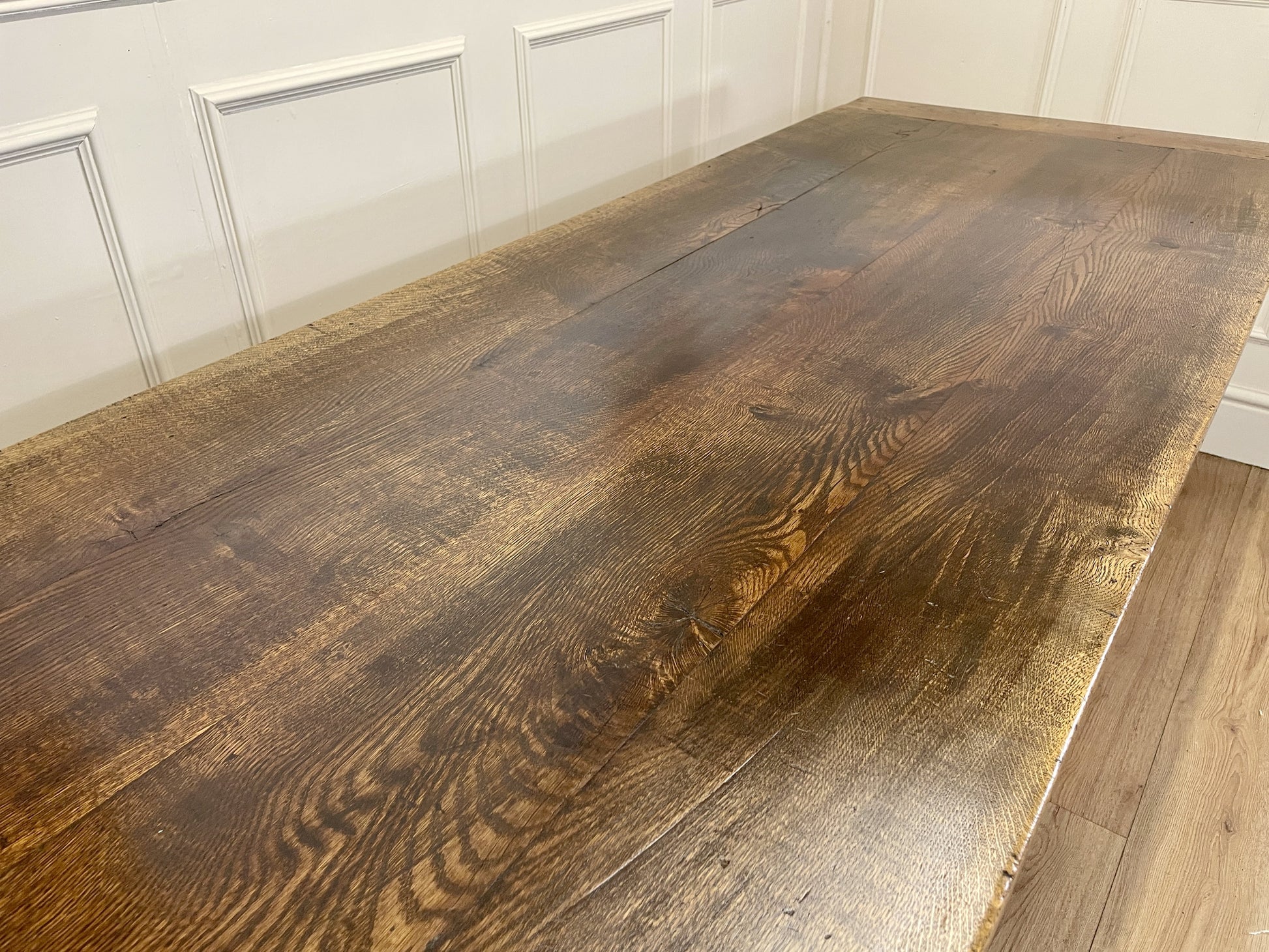 Wooden table with a dark finish against a white paneled wall.