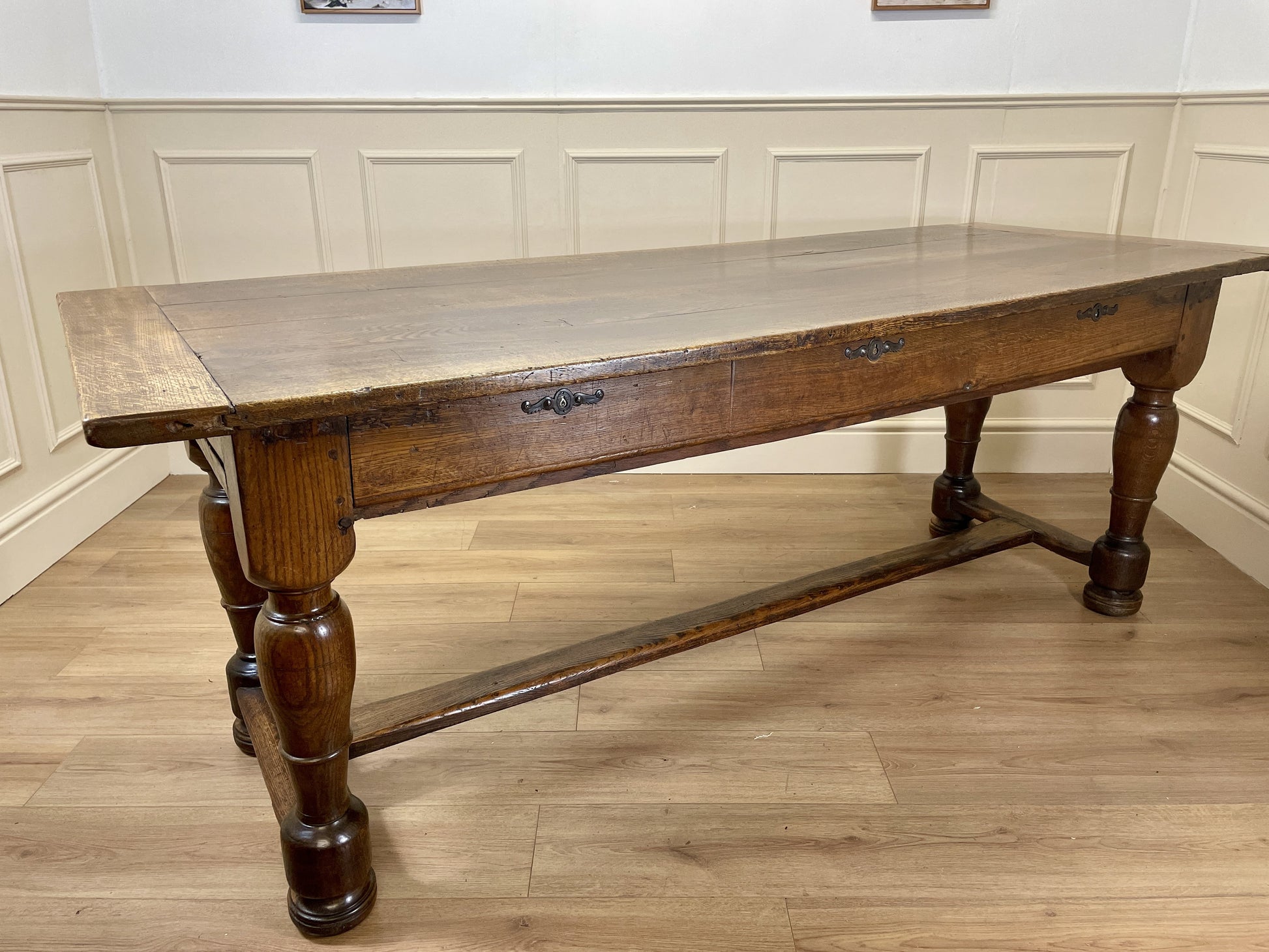 Wooden table with a glass top in a room with paneled walls.