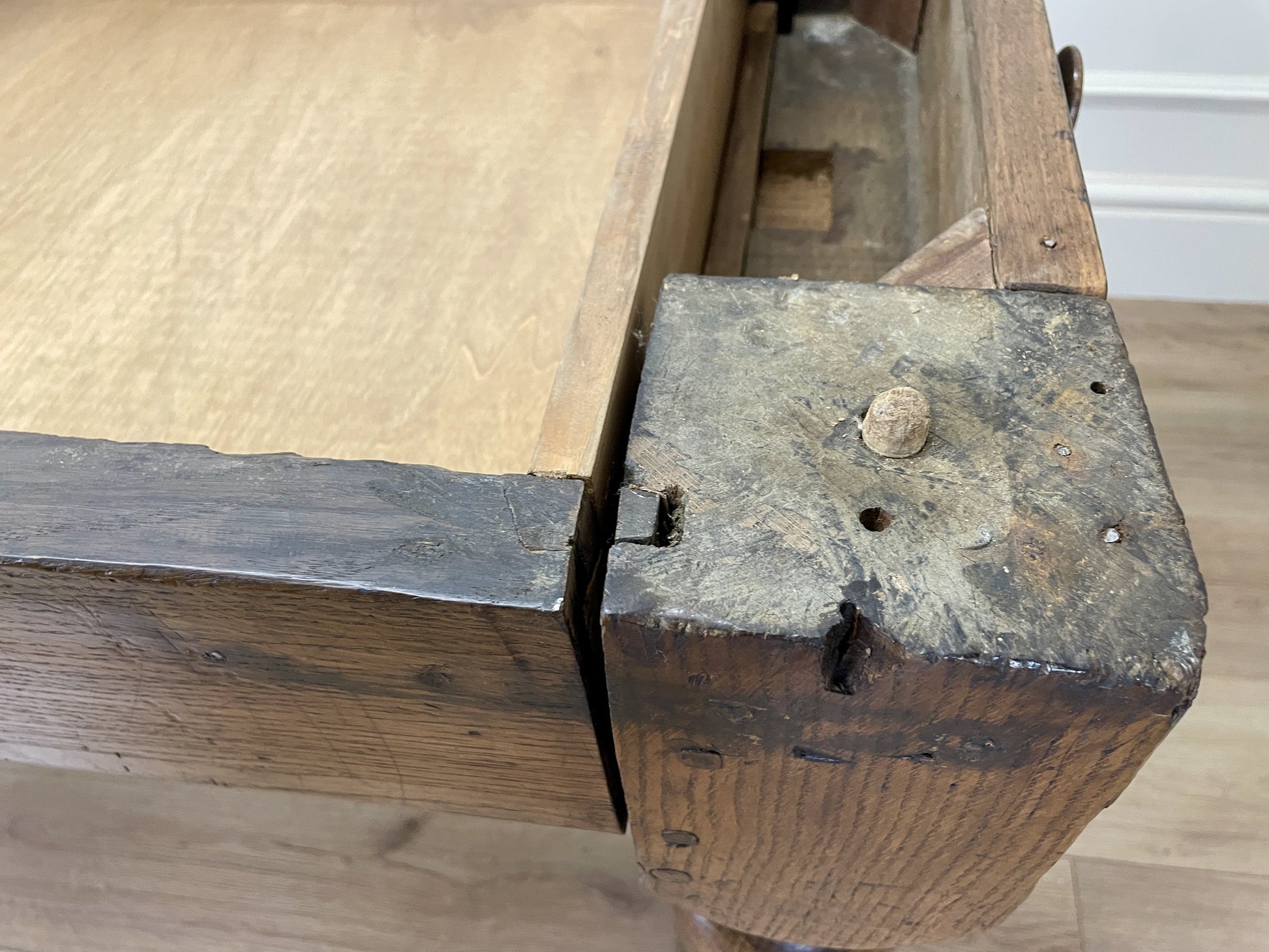 Close-up of an old wooden bench with metal bracket on a wooden floor.