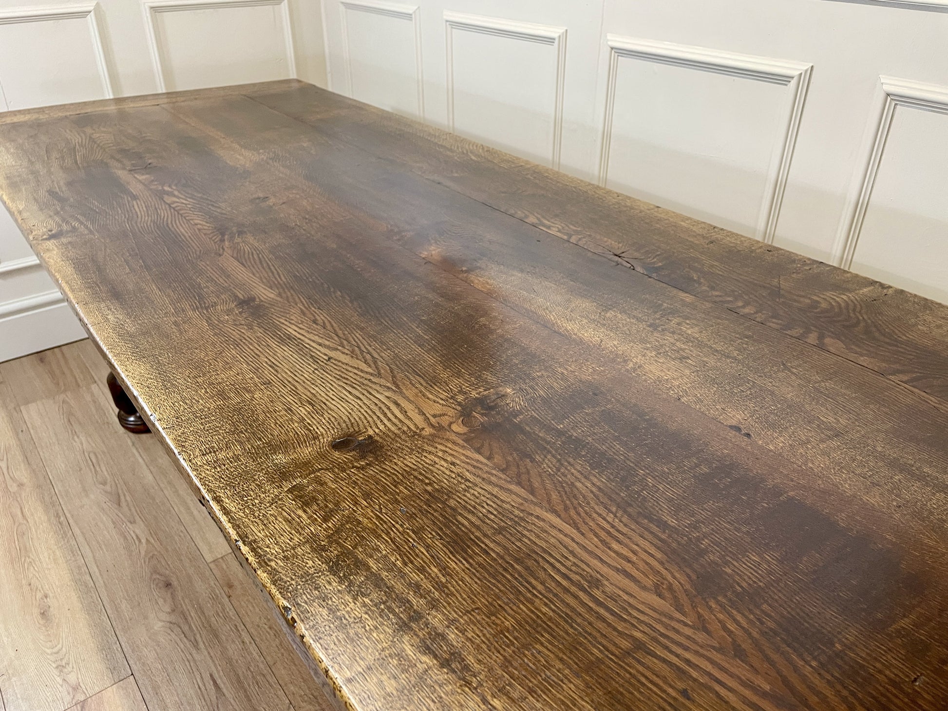 Large wooden table with a rustic finish in a room with white paneled walls.