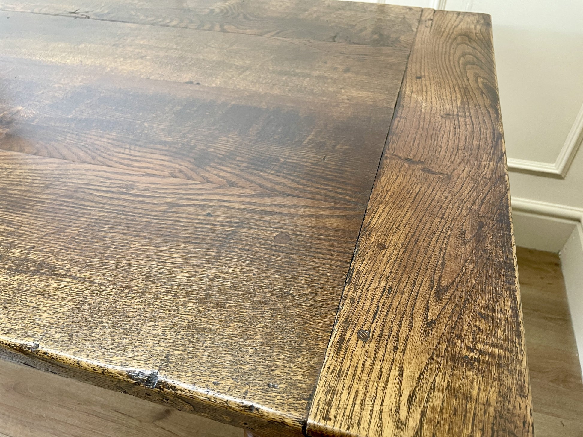 Close-up of a wooden table corner with visible grain and texture.