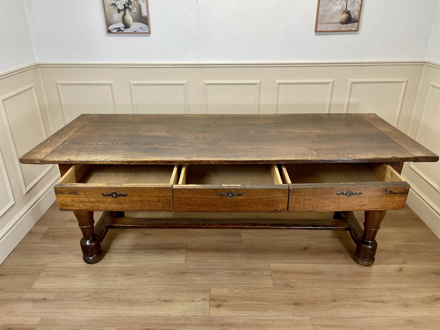 Wooden desk with drawers in a room with panelled walls and wooden flooring.