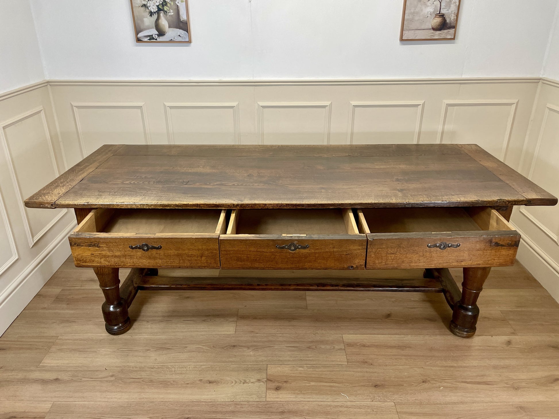 Wooden desk with drawers in a room with panelled walls and wooden flooring.