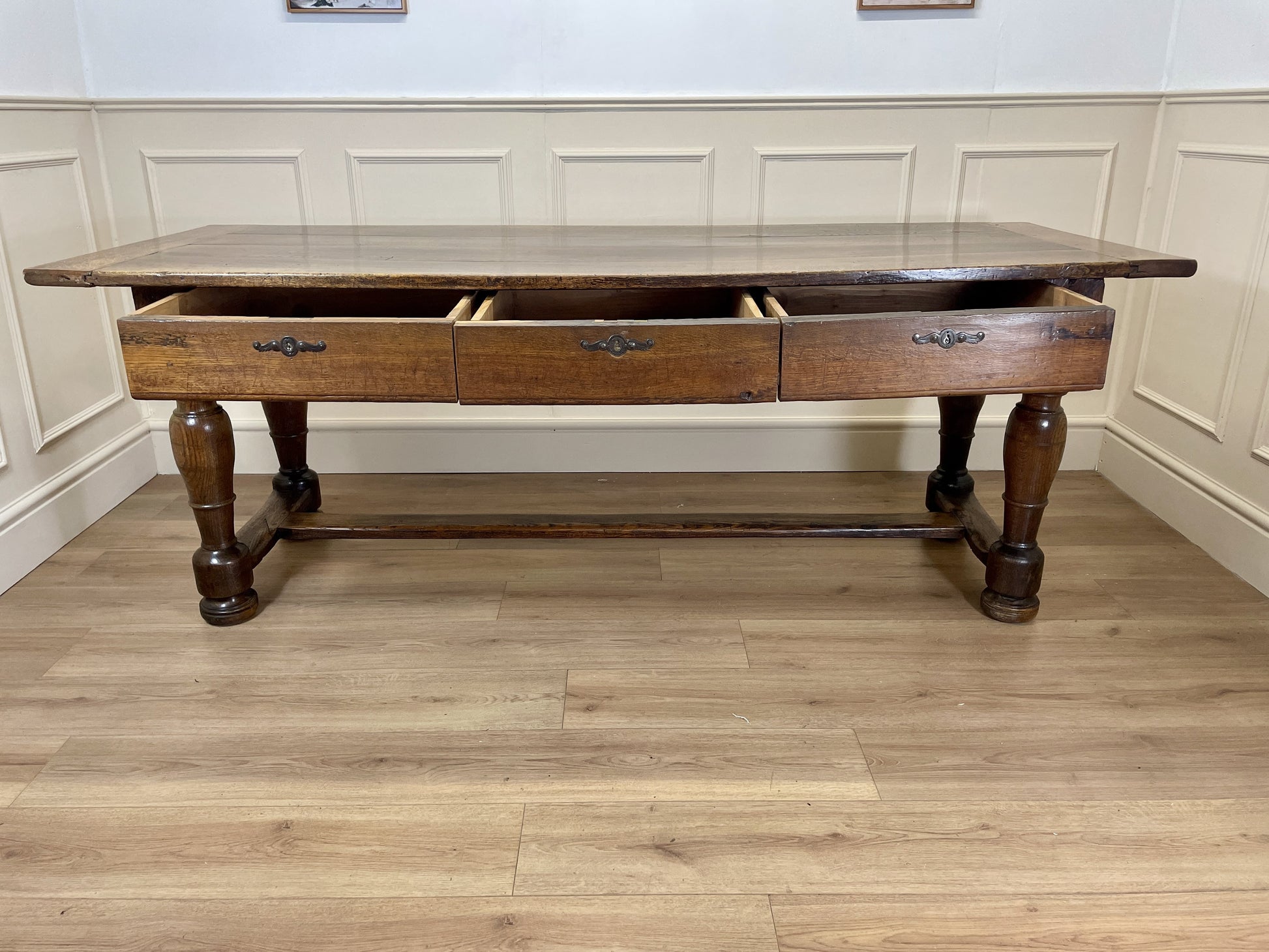 Wooden table with drawers in a room with panelled walls and wooden floor.