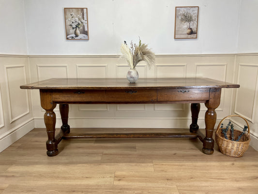 Wooden dining table with a shelf against a white paneled wall.